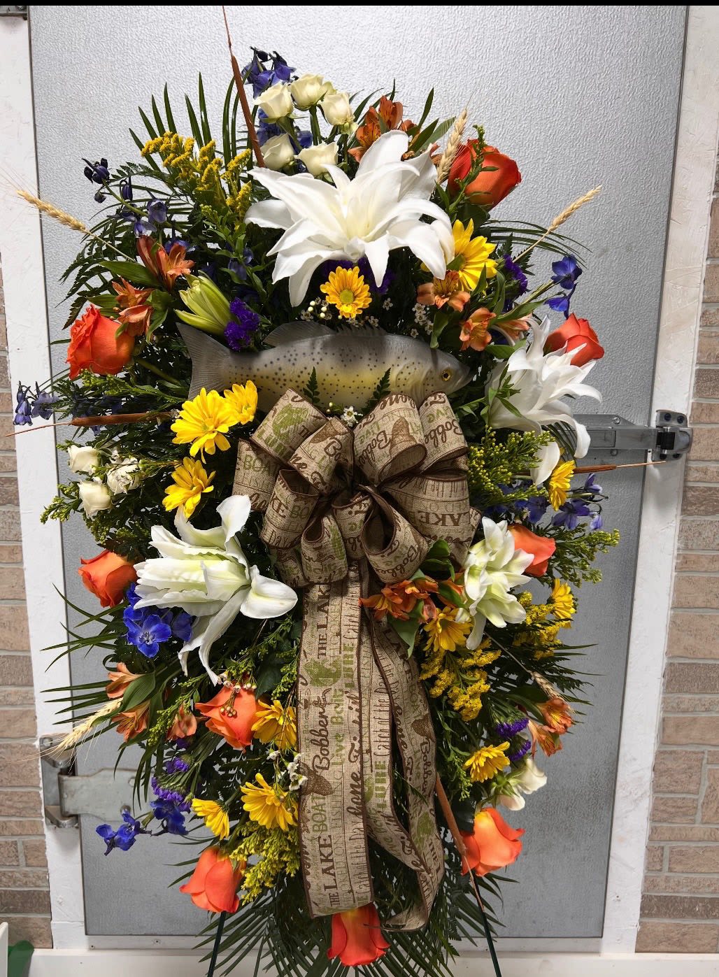 Gone Fishing Standing Spray  - Celebrate the life and passions of a loved one with our Fishing-Themed Standing Spray. Thoughtfully designed with a beautiful blend of fresh blooms and fishing-inspired accents, this tribute honors a spirit who loved the water, the outdoors, and the peaceful art of fishing. Displayed on a sturdy easel, it brings a personalized and heartfelt touch to funeral services, memorials, or celebration of life ceremonies.