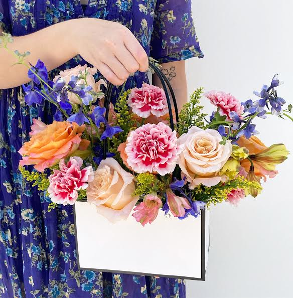 The Sophie - Indroducing, Sophie! The cutest addition to our summer line-up of floral lovelies. This arrangement is designed in a cute, yet sophisticated, &quot;purse&quot; with a nod to Chanel. Full of gorgeous garden roses and shouts of vintage French carnations, this colorful combination will delight at any age. The flower purse is designed all the way around and call also make a great centerpiece or birthday gift.