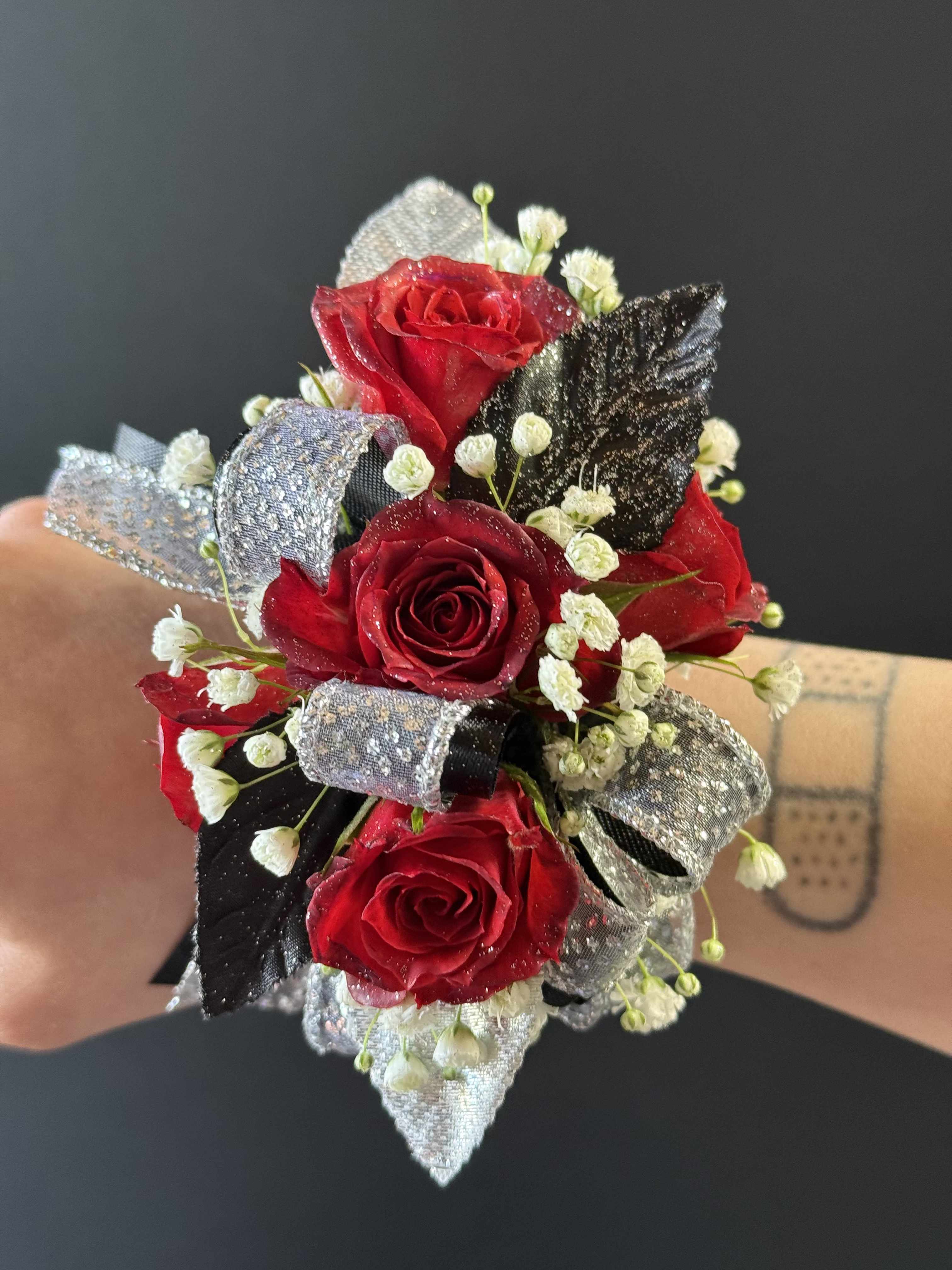 Red spray rose corsage - Red roses with baby's breath, sparkly silver and black ribbon, black and silver leaves.