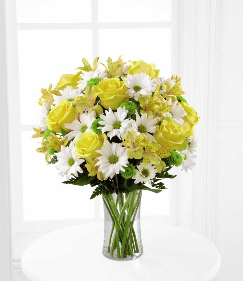 The Sunny Sentiments Bouquet The Sunny Sentiments Bouquet - The Sunny Sentiments Bouquet is a blooming expression of charming cheer. Brilliant yellow roses and Peruvian Lilies are paired with white traditional daisies and green button poms to create a memorable bouquet. Accented with lush greens and arranged in a classic clear glass vase, this bouquet is a wonderful way to celebrate any of life's special moments.