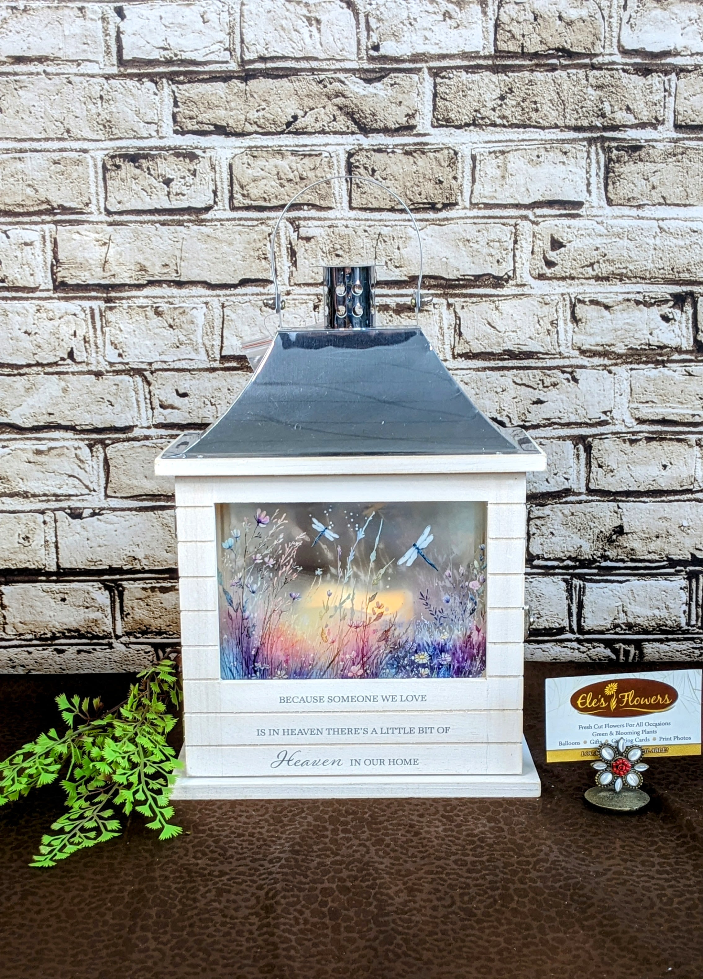 Heaven in our Home - Sympathy Lantern - A wonderful keepsake lantern to remember a loved one. This lantern is constructed of wood material with a decorative silver top and painted dragonflies and flowers. The phrase &quot;Because someone we love is in Heaven, there's a little bit of Heaven in our home&quot; printed on the front. For indoor use only. Our Sympathy lanterns are powered by 3 AAA batteries (included). A flicker candle illuminates the lantern.  Approximate Dimensions: 14&quot;H x 9&quot;W