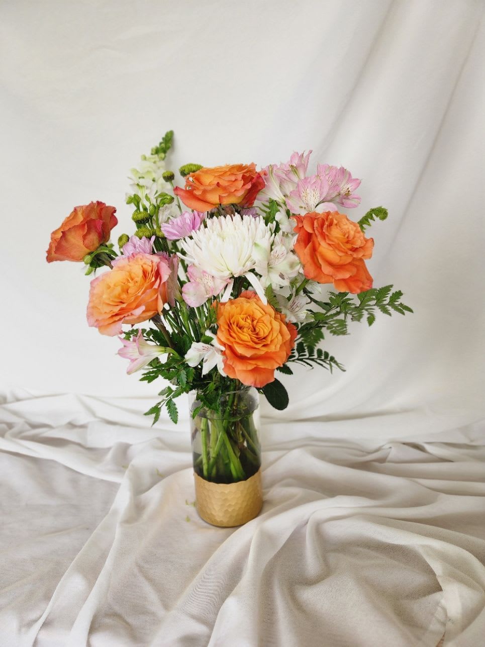 Golden Grove - Golden Grove is a radiant celebration of warmth and elegance. Vibrant orange roses bloom brightly in a clear green vase, accented with a touch of gold trim at the base for an extra hint of luxury. This stunning arrangement captures the spirit of a sun-drenched garden, blending fresh, lively color with refined beauty. Perfect for brightening any space or marking a special moment, Golden Grove brings a cheerful yet sophisticated charm wherever it goes.  Great arrangement to get your loved ones for Mother's Day