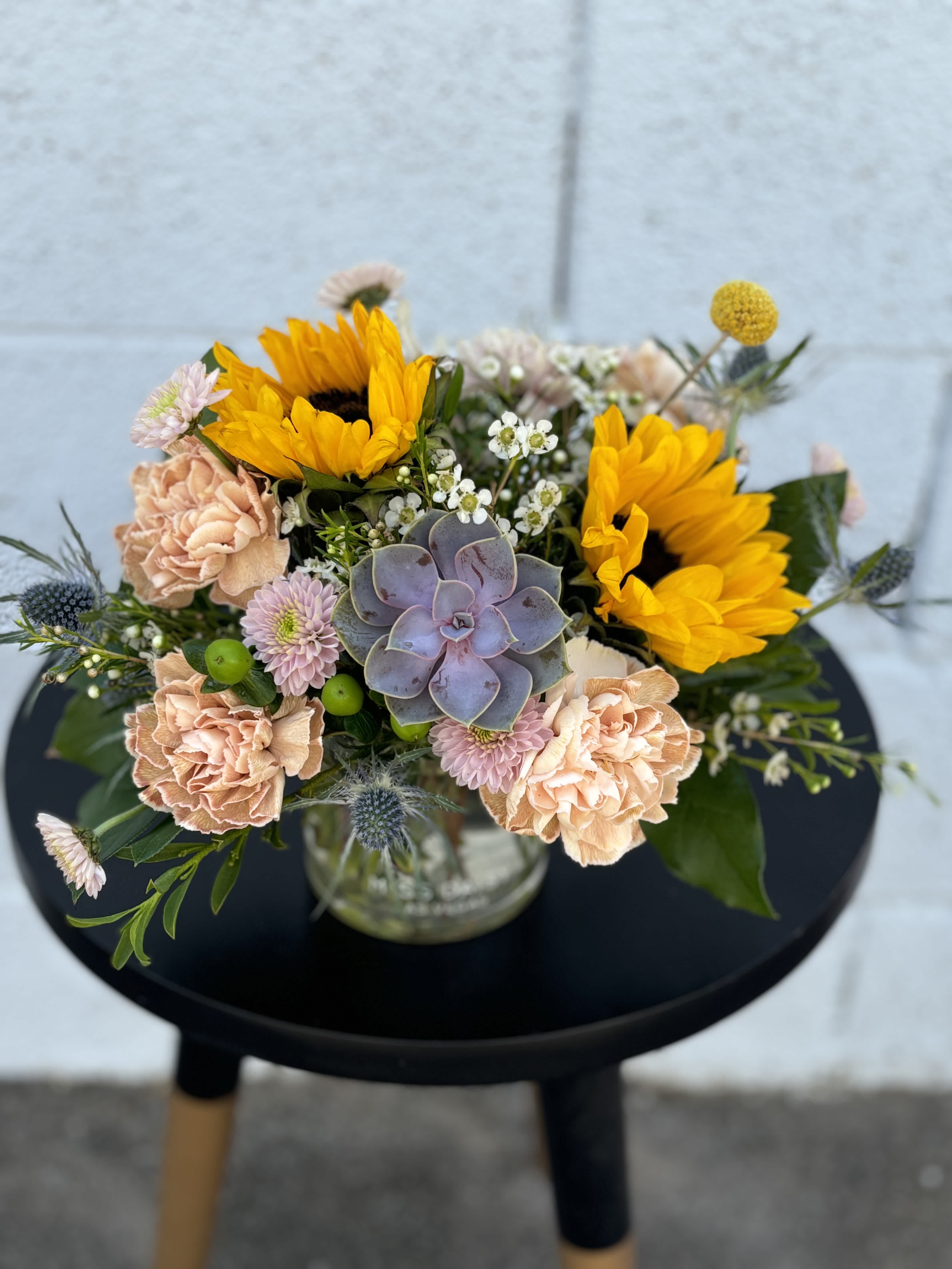 Sunny Succulents - Bring the warmth of a sunny day indoors with our exquisite Sunny Succulents bouquet! This arrangement features a delightful blend of vibrant sunflowers, fun succulents and other botanical textures. Perfectly curated to brighten any space, this arrangement embodies the beauty of nature's contrasts.