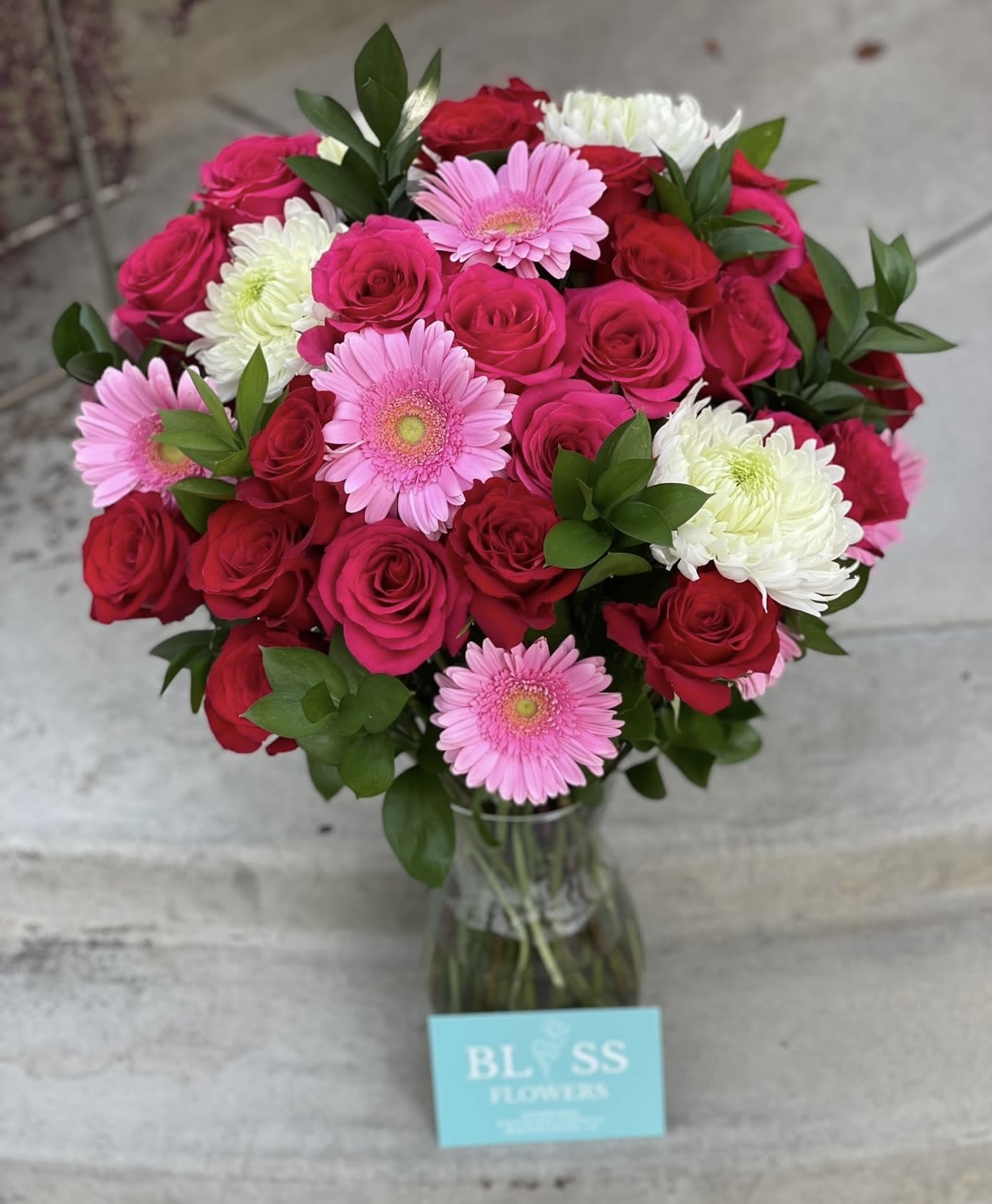 Color me pink Color me pink - A colorful mix of roses, daisies and mums make up this simple yet elegant arrangement.