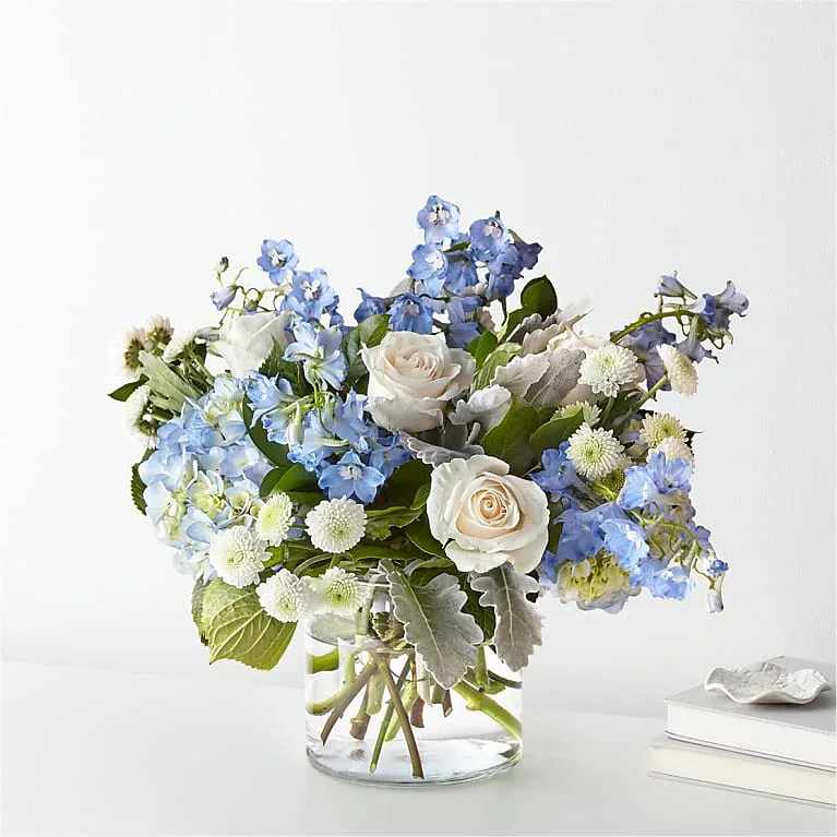 CLEAR SKIES BOUQUET - Let this uplifting arrangement be reminders of the clear skies ahead. Capturing the feeling of hope that a new day brings, this bouquet is composed of voluminous hydrangea blooms and vibrant belladonna delphinium to refresh their mood. The Exquisite Bouquet is approximately 19&quot;H x 24&quot;W. Designed by florists, ready to display. For long–lasting blooms, replace the water daily. We suggest trimming the stems every couple days. Pet Safety Precautions: This bouquet or plant may include flowers and foliage that are known to be toxic to pets. To keep them safe, be sure to keep this arrangement out of your pet's reach. BLOOM DETAILS  Delphinium Hydrangea Rose  To guarantee the freshest bouquet possible, our florists may replace some stems in your arrangement which could differ in color and variety. See Substitution Policy