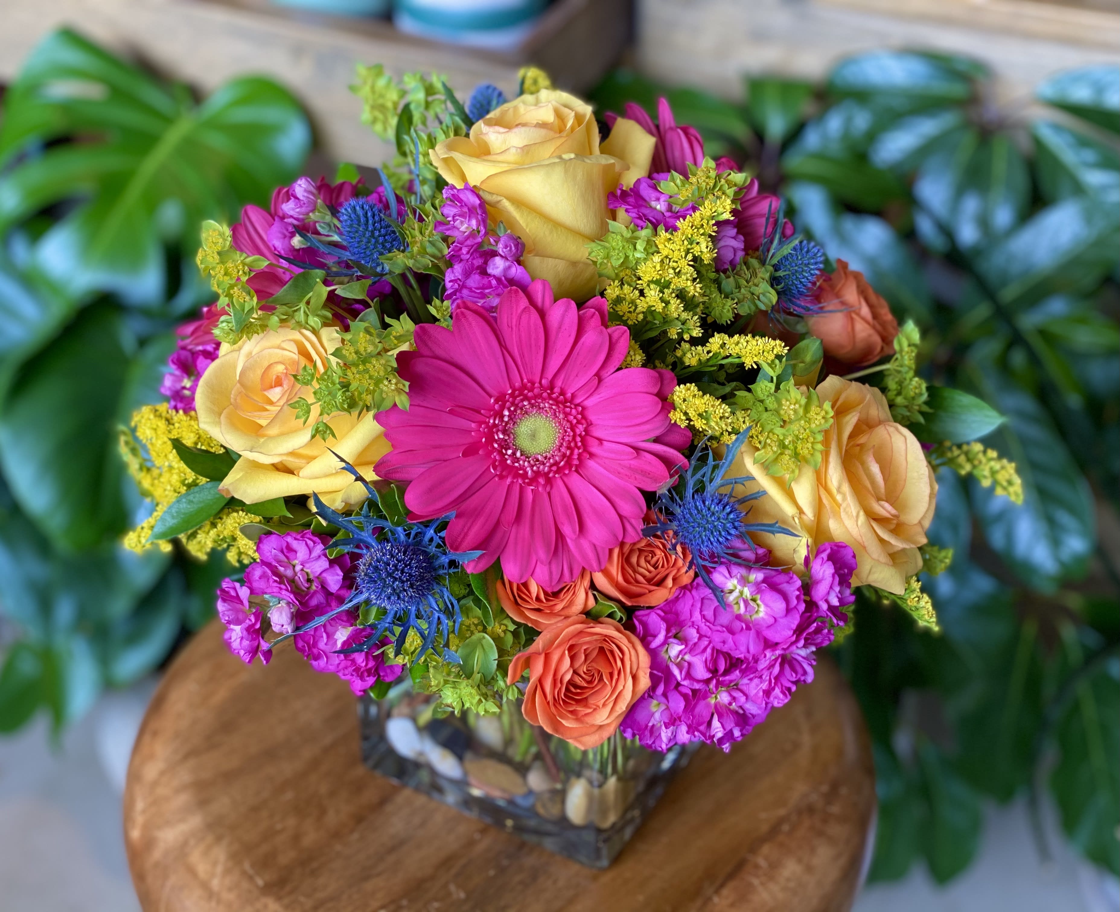 The Fleur by Simply Fresh Flowers - Designed in a premium 5&quot; glass cube, The Fleur, boasts gerbera daisies, roses, spray roses, stock &amp; thistle amidst a bed of assorted greens.  An all sided design perfect for the gerbera daisy lover!