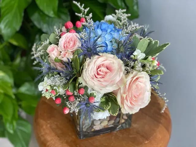 The Mia by Simply Fresh Flowers - The Mia, one of our bestsellers, is a lovely, all sided vase arrangement, designed in a premium 5&quot; glass cube with Columbian blue hydrangea, Ecuadorian pink roses, white stock, spray roses, blue thistle &amp; hypericum berries. Simply lovely for any occasion!