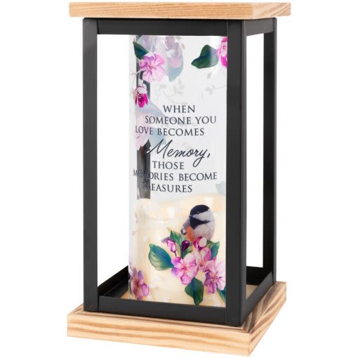 LANTERN &quot;MEMORIES BECOME TREASURES&quot; - Our framed cylinder lanterns are comprised of a flameless LED candle inside a glass cylinder that is framed with wood and metal. The cylinder is adorned with full color artwork. The candle features an automatic timer that runs for 6hrs ON and 18hrs OFF which requires 3AAA batteries that are NOT included. Indoor use only!  Lantern Reads: &quot;When someone you love becomes a memory, those memories become treasures&quot;  W: 4.75&quot; H: 8.5&quot; D: 4.75&quot;  Price includes bow