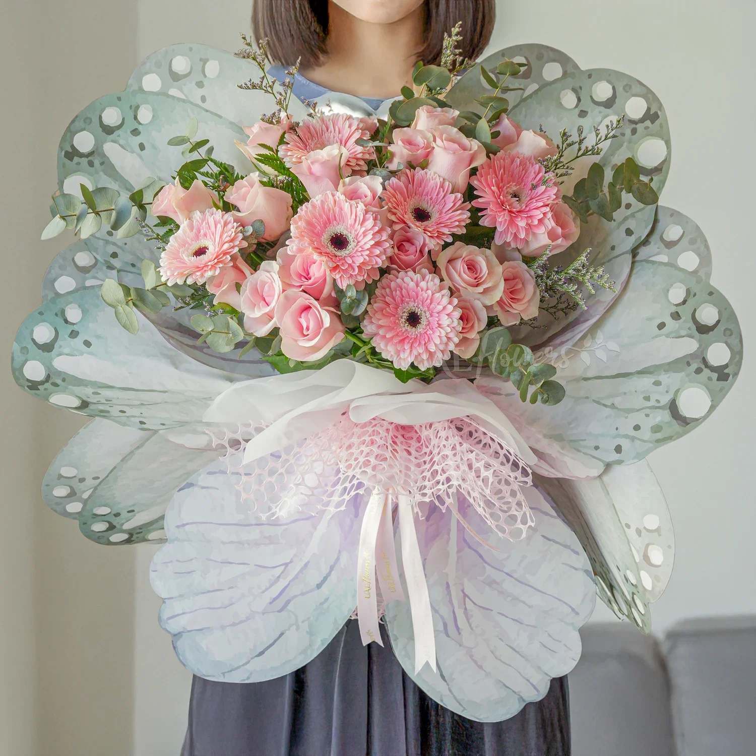 Butterfly Bliss Bouquet Butterfly Bliss Bouquet - This charming butterfly-shaped bouquet features vibrant pink gerberas paired with 6pink roses. Accented by delicate limonium and fresh green fillers, the bouquet is tied with elegant ribbons, creating a soft and joyful arrangement perfect for any special occasion or heartfelt gesture.