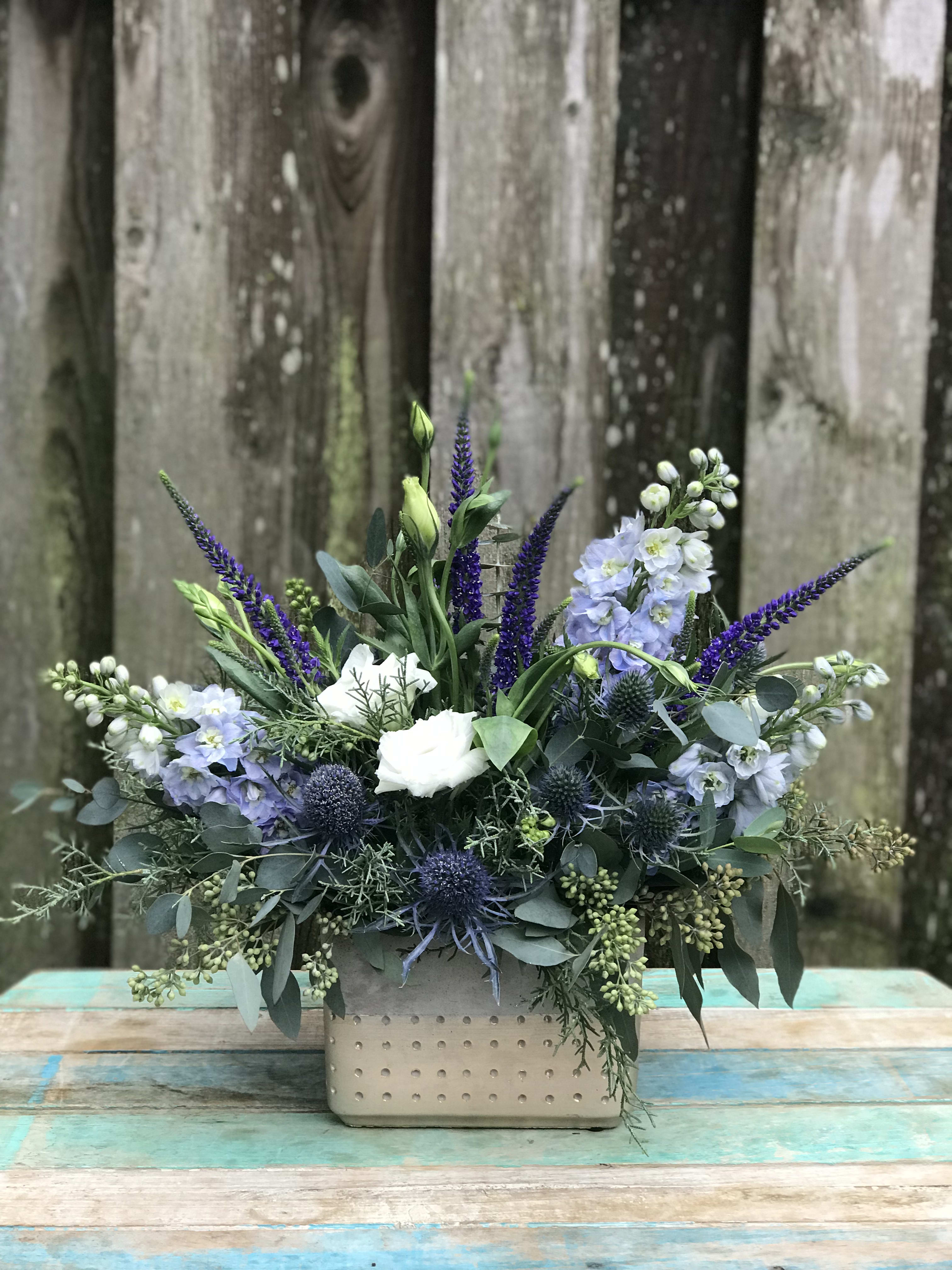 Best Wishes Best Wishes - Textured whites, blues and silvery greens gathered in a modern container create a bright and promising mix perfect for any occasion. Vase vary depending on availability.