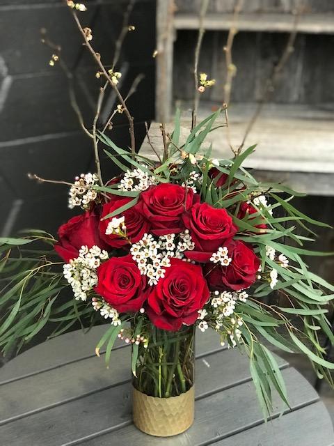 Glamorous Glamorous - A dozen red roses with a touch of white and green and blooming quince branches or curly willow gathered in a glamorous vase. Vases vary depending on availability.