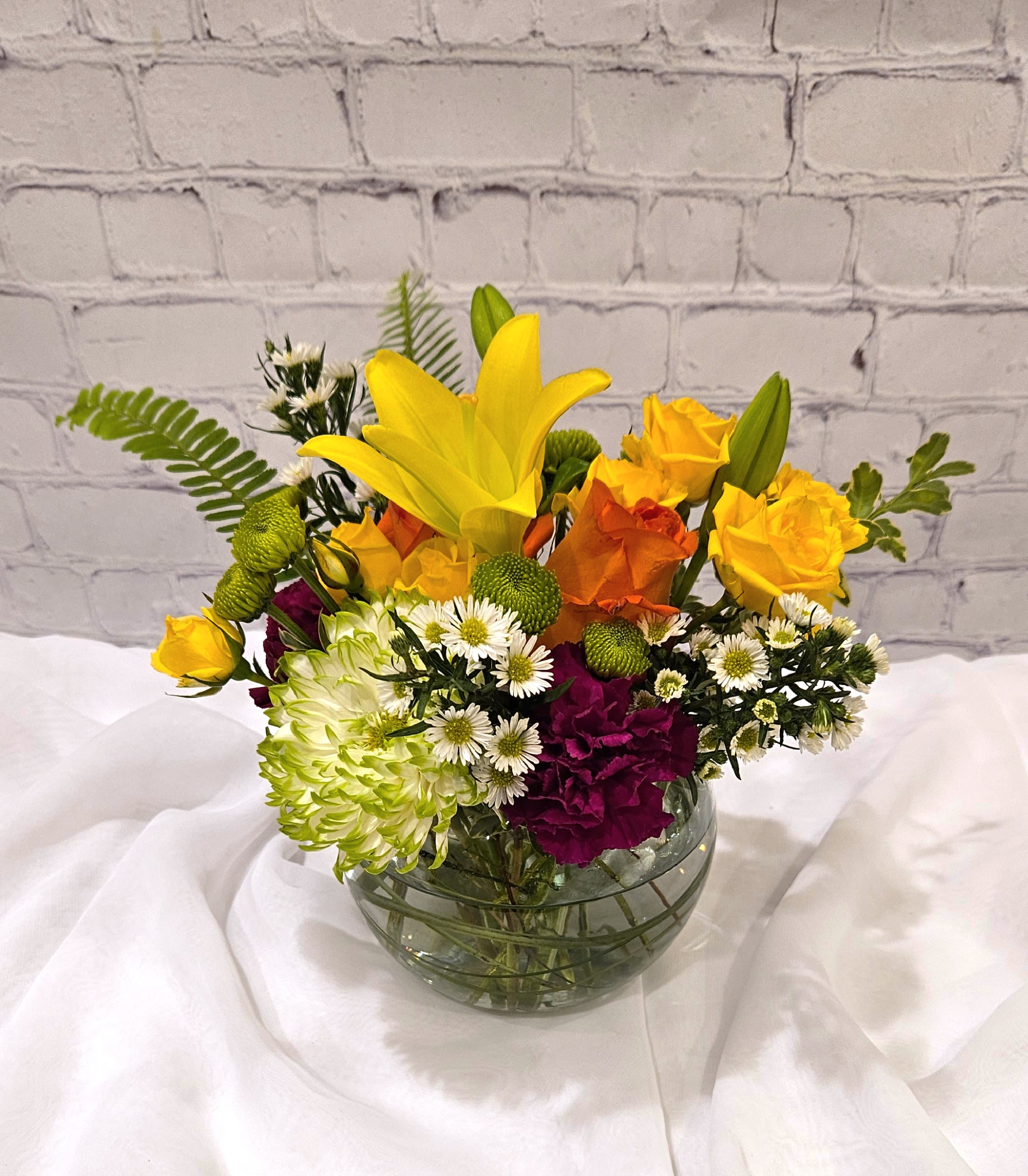 Color-full Surprises - Dazzling jewel tone hues bring delight packed into this desktop sized arrangement.  Colorful lilies, carnations, roses and more. 