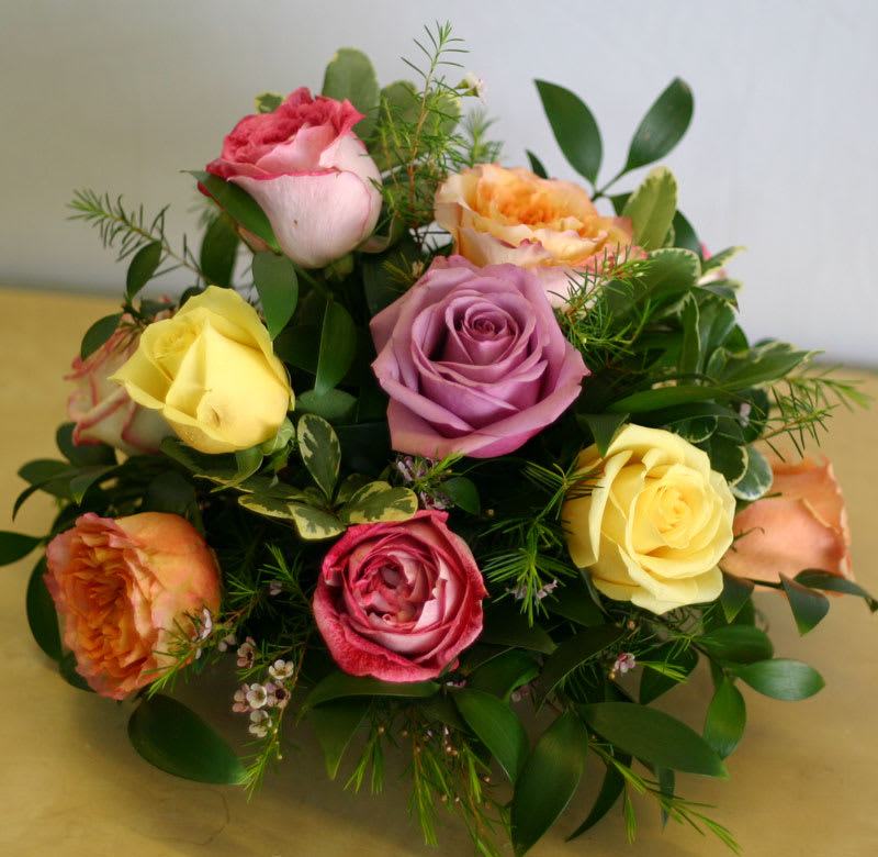 Dozen Roses Centerpiece - One dozen mixed color roses arranged in a lower all-around centerpiece style perfect for the dinner table, a smaller apartment, the bedroom, or an office desk.