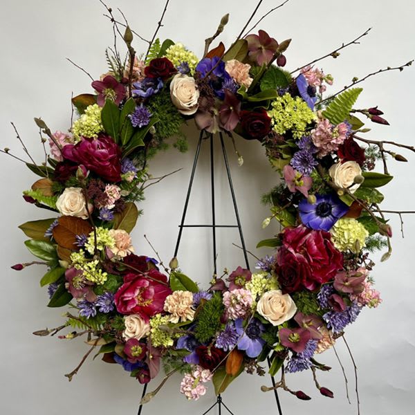 Celebration of Life Wreath - A beautiful mix of seasonal flowers that is bright, celebratory and yet comforting.  Colors and flower choices may vary due to the season and availability but the design will retain the overall look and feel of the wreath pictured.  