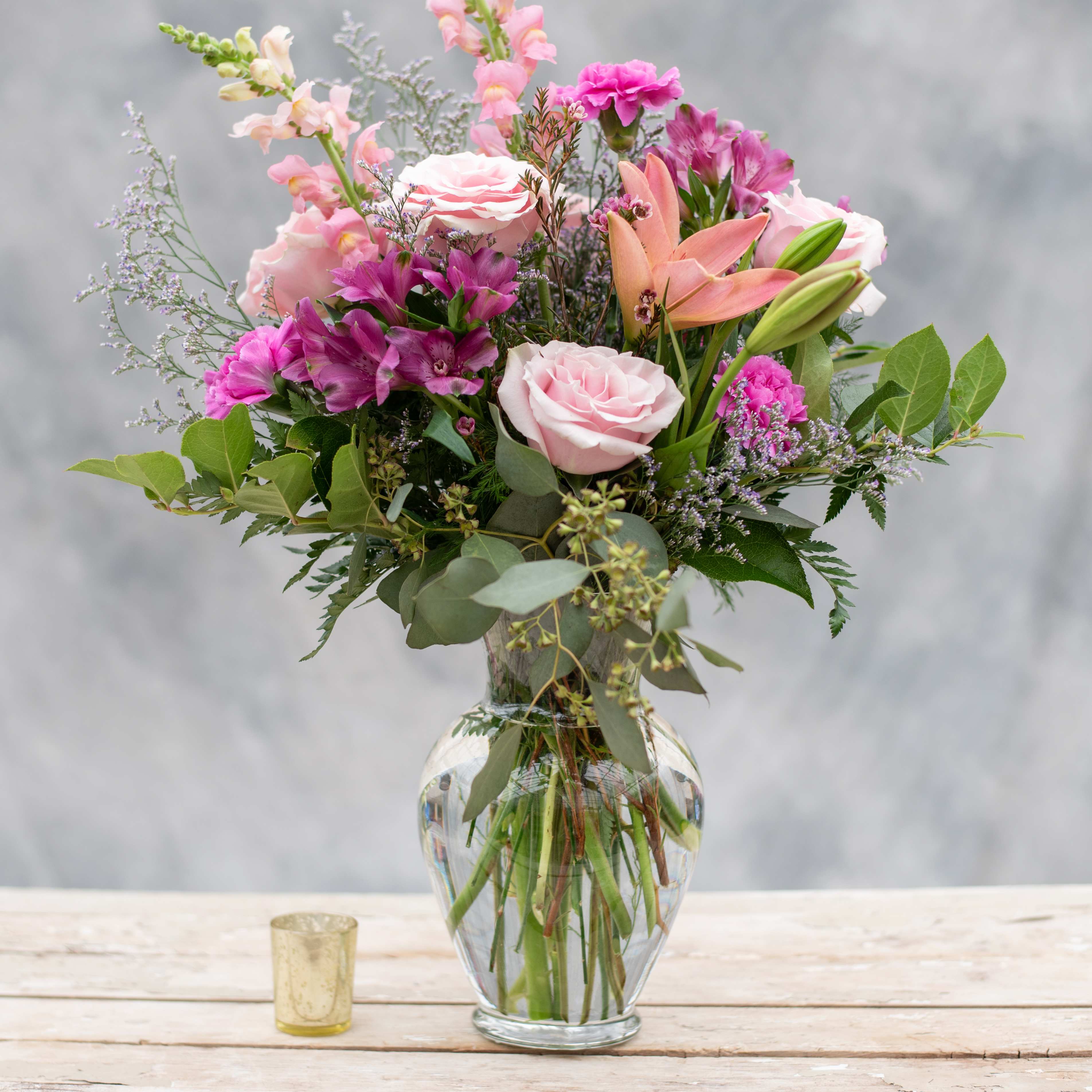 Mother's Delight - Surely to Delight any Mother, this beautiful 10.5&quot; classic clear vase overflowing with pinks and lavenders, and purples, including roses, lilies, snapdragons, alstroemeria, carnations and premium greens.   