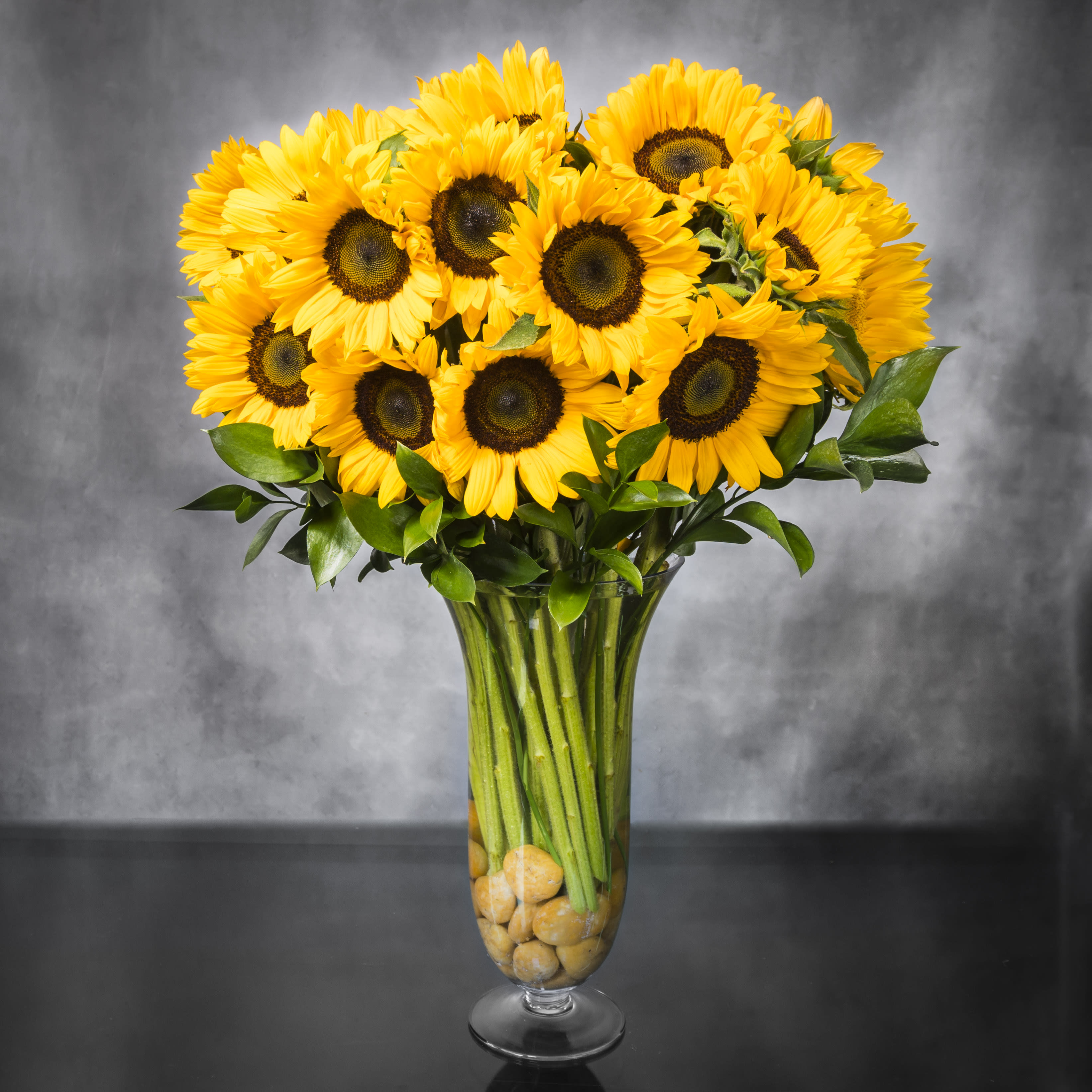 Baby it's Sunny Outside - A fresh breath of beautiful Sunflowers that add a bright touch to the room. Even with its bright tones it has a classic simplicity that is something that cannot be missed.   Sunflowers in classy vase with pebbles. approx 30&quot; Tall 