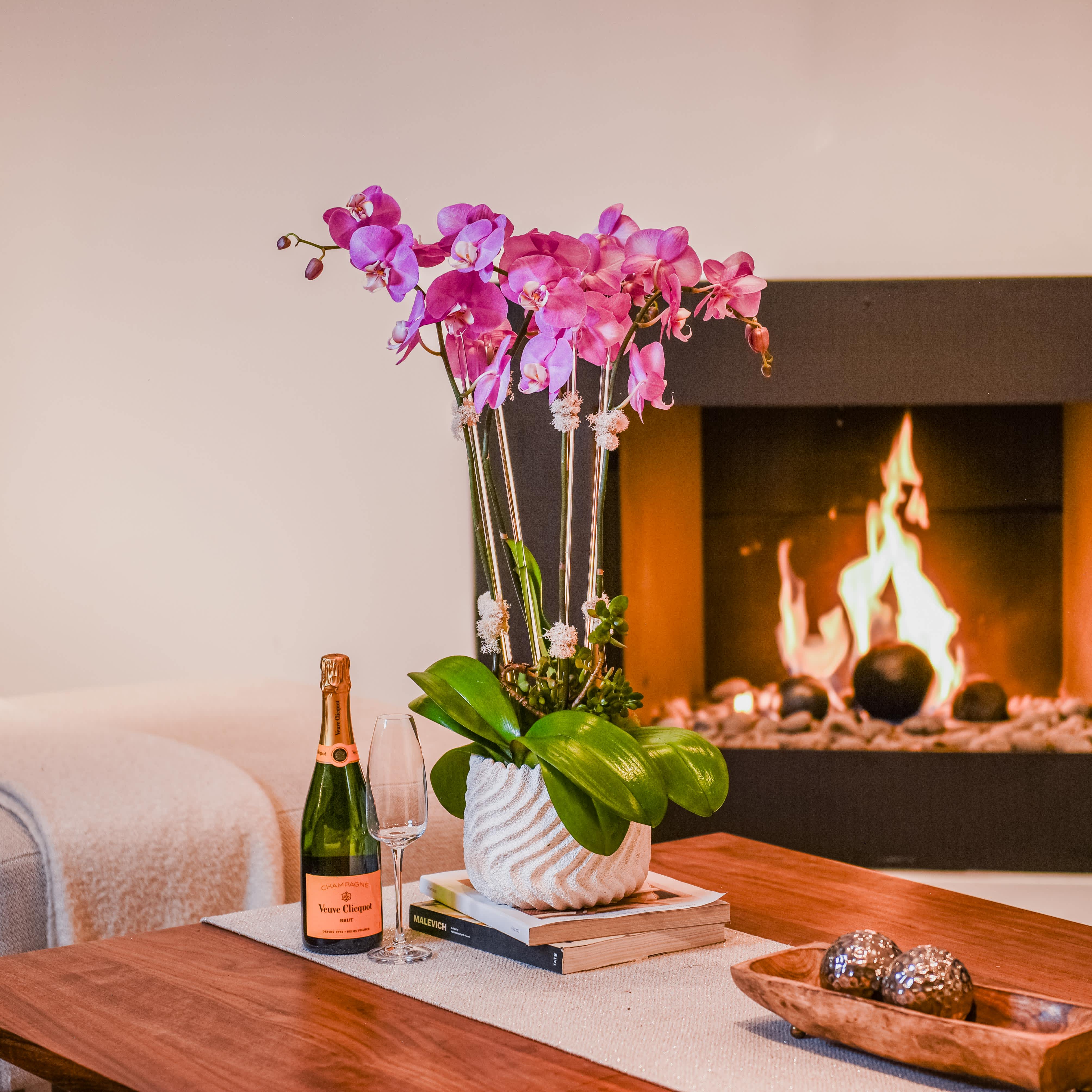 Rosy Glow 2.0 Rosy Glow 2.0 - Embrace the vibrant allure of our Hot Pink Orchid Stem Duo, poised elegantly within a shorter ceramic vase. Each stem boasts a profusion of vivid pink blooms, radiating warmth and vitality with every petal unfurled. These enchanting orchids command attention, their bold hues igniting a passion for beauty and life. Against the backdrop of the sleek ceramic vessel, the striking contrast of color and form creates a captivating tableau, a symphony of hues dancing in harmonious unity. Whether gracing a chic dining table or adorning a contemporary foyer, let these dazzling orchids infuse your space with a burst of energy and joie de vivre, a testament to the vibrant splendor of nature's bounty.