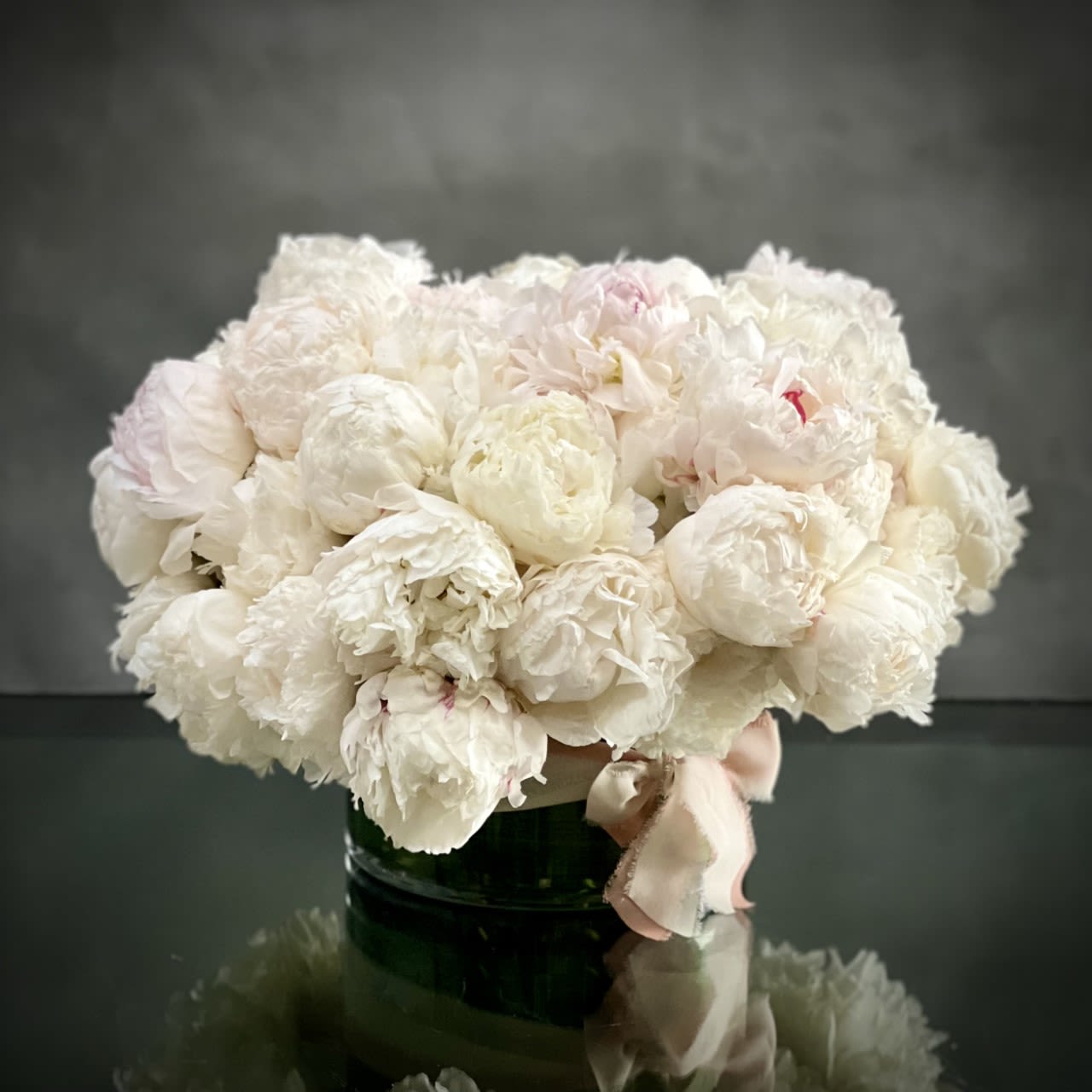 White Blush Peony Wonder White Blush Peony Wonder - White and blush peony arrangement nested in a simple glass vase with a bow. It's beautiful in itself without any other floral. AS SHOWN DELUXE