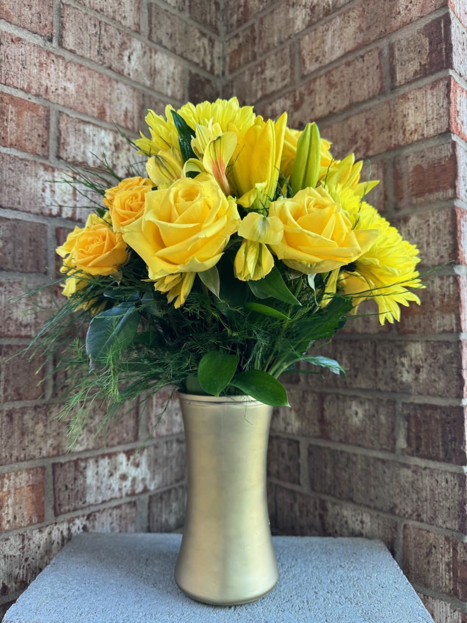 Golden Anniversary - The &quot;Golden Anniversary&quot; arrangement is a vibrant and elegant display of sunshine and joy. It features radiant yellow roses, bright yellow lilies, and golden chrysanthemums, all beautifully arranged among lush green foliage. The flowers are showcased in a sleek, modern golden vase, perfectly complementing the theme and adding a touch of sophistication. This arrangement is ideal for celebrating special milestones, bringing warmth and positivity to any space, or sending a message of cheer to someone special.