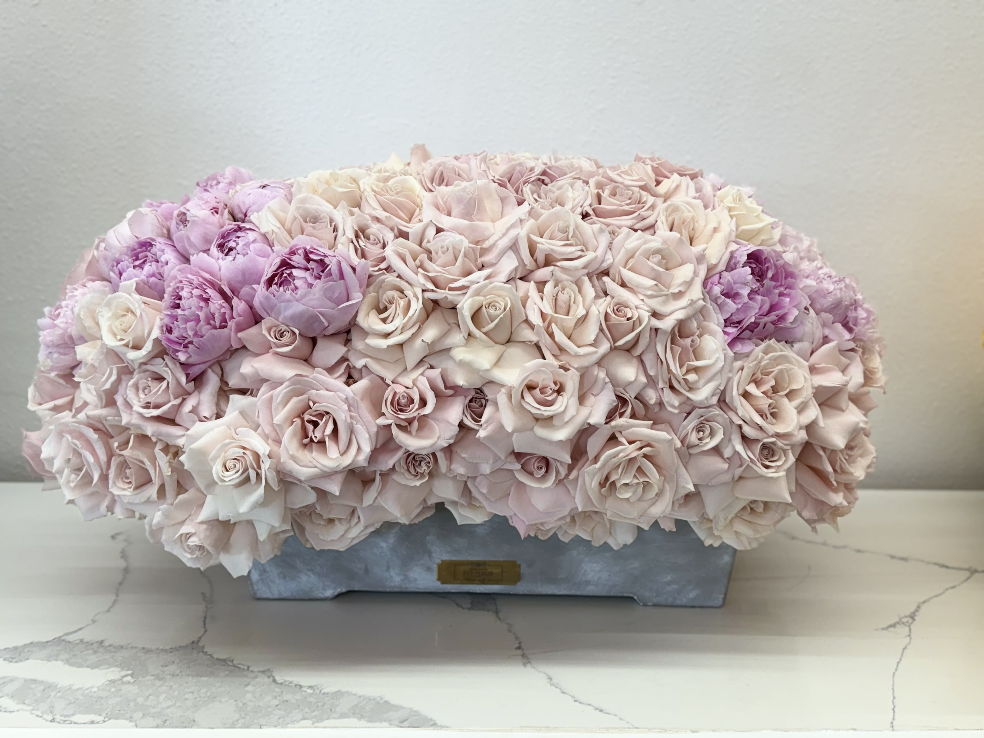 Expressing my Love  - **Grand Rose and Peony Arrangement: A Stunning Expression of Love**  Surprise your loved one with our breathtaking grand arrangement featuring a vibrant mix of luxurious roses and delicate peonies. This eye-catching display is designed to make a bold statement, perfect for anniversaries, birthdays, or just because you want to show how much you care.  Each arrangement showcases the lush beauty of velvety roses, complemented by the soft, ruffled petals of fresh peonies, creating a stunning contrast that captivates the senses. The rich colors and fragrant blooms evoke feelings of romance and admiration, making this a truly unforgettable gift.  Skillfully arranged to highlight the natural beauty of each flower, this grand bouquet is perfect for placing in a prominent spot where it can be admired and cherished. Whether it’s for a special occasion or a spontaneous gesture of love, this arrangement is sure to amaze and delight your loved one, leaving them with a lasting impression of your thoughtfulness and affection. Celebrate love in all its forms with this exquisite floral masterpiece!