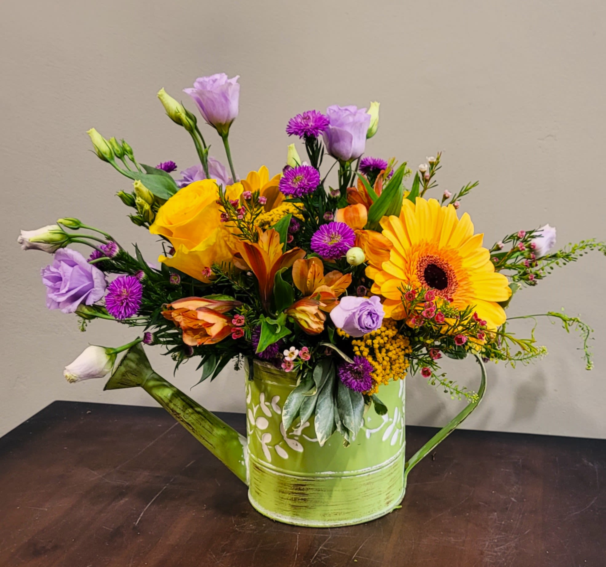 Spring Showers  - A colorful hammered watering can with an assortment of seasonal blossoms with Lisianthus, Alstroemeria, Sweet William, Gerbera Daisies, Tulips,  and so much more.                                                                                                    * Request your favorite color – pink / blue / green   