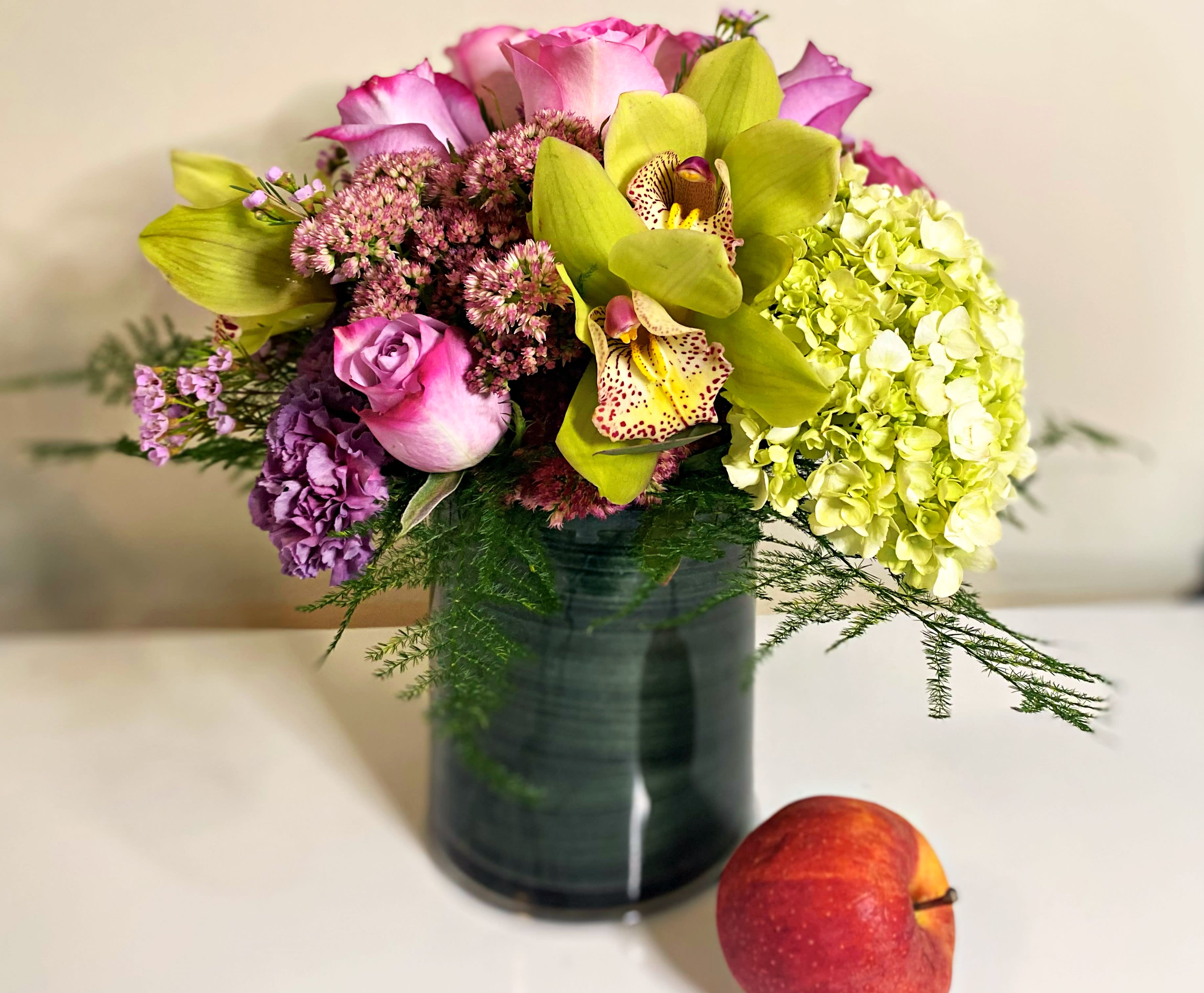 The Green and Lavender  - Vibrant modern design of green pink and lavender premium flowers. Roses,orchids and hydrangea in a cylinder. Perfect for a birthday, thank you, baby girl, Mother’s Day gift and get well. We will use the freshest floral available and keep the same stylized design. We might need to substitute and you will be notified by email. 