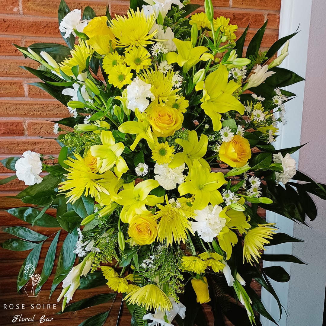 Rays of Sunshine - This vibrant funeral easel will evokes thoughts of happy times and shunshine. Featuring a variety of white, vibrant yellow florals with lush greenery this elegant funeral easel brings a feelings of  comfort to those grieving their beloved.