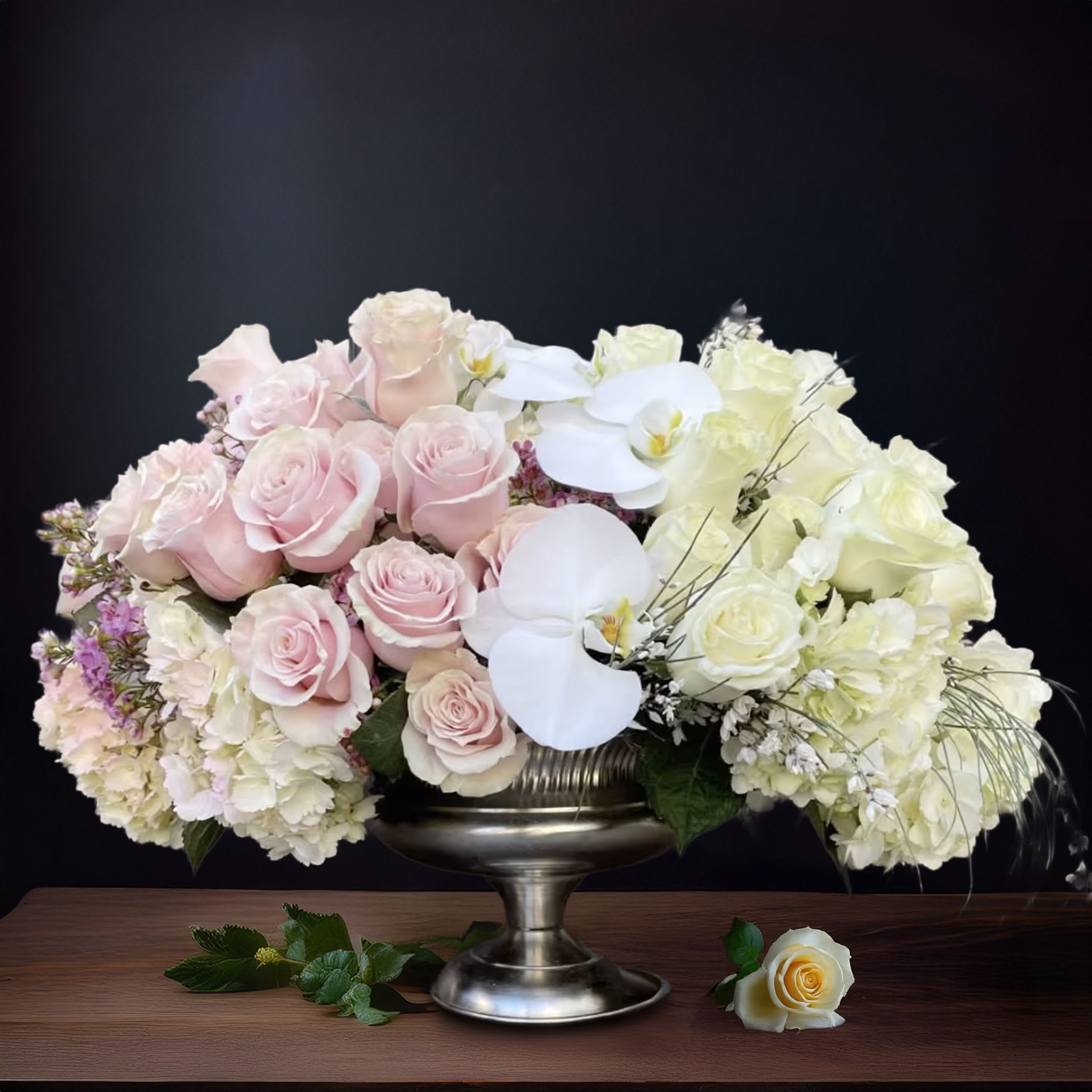 Charmed <3 Charmed <3 - Timeless and grand, this exquisite arrangement features an opulent blend of blush roses, white phalaenopsis orchids, and ivory hydrangeas, all gracefully styled in a vintage-inspired silver compote vase. With its soft, romantic palette and elegant presentation, this piece is perfect for luxury weddings, formal dinners, or as a dramatic statement piece for upscale home décor. Designed by Touch Of Orchids LA, it reflects the essence of classic floral sophistication, ideal for clients in Pasadena, Bel-Air, Beverly Hills, and Malibu seeking an arrangement that feels both regal and refined. Whether displayed on a grand piano, at the center of a lavish tablescape, or at the entrance of a wedding venue, this arrangement delivers timeless elegance with a modern touch. Each bloom is carefully placed for balance, grace, and impact — making it one of the most requested styles for celebrity events, private estate gatherings, and luxury flower delivery in Los Angeles.