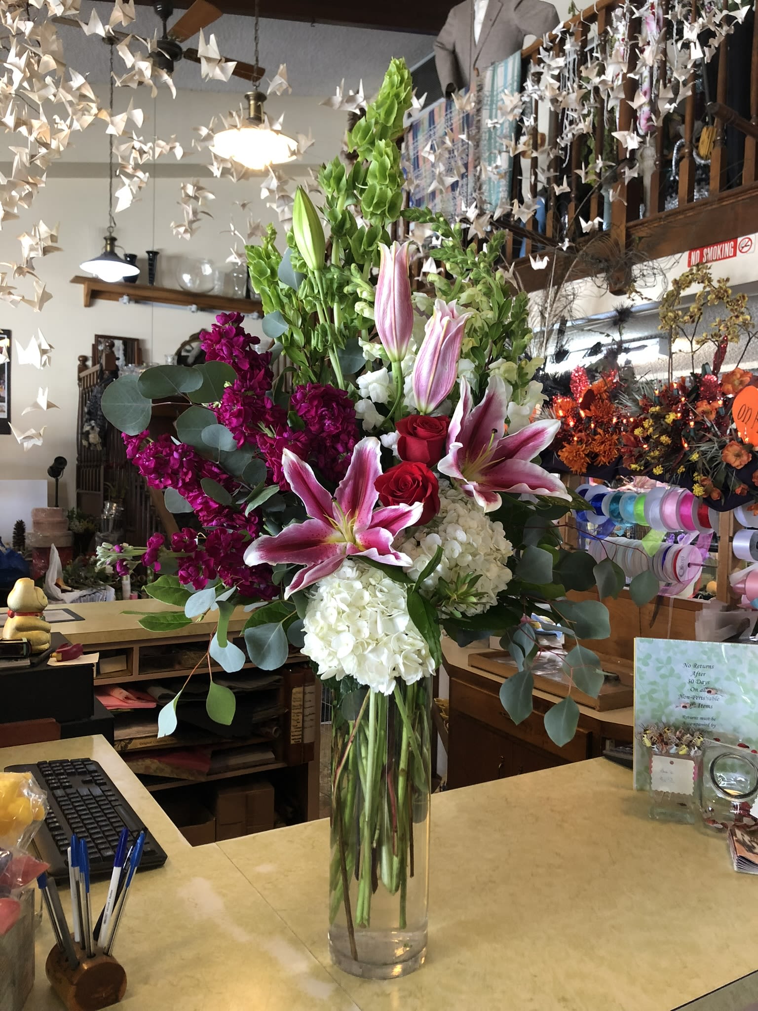Lilies, Hydrangea, Roses and More Lilies, Hydrangea, Roses and More - Snowy white hydrangea, partnered with crimson roses, bold stargazers, delicate stock, fresh green bells of Ireland, and whimsical snapdragons to convey your special message.