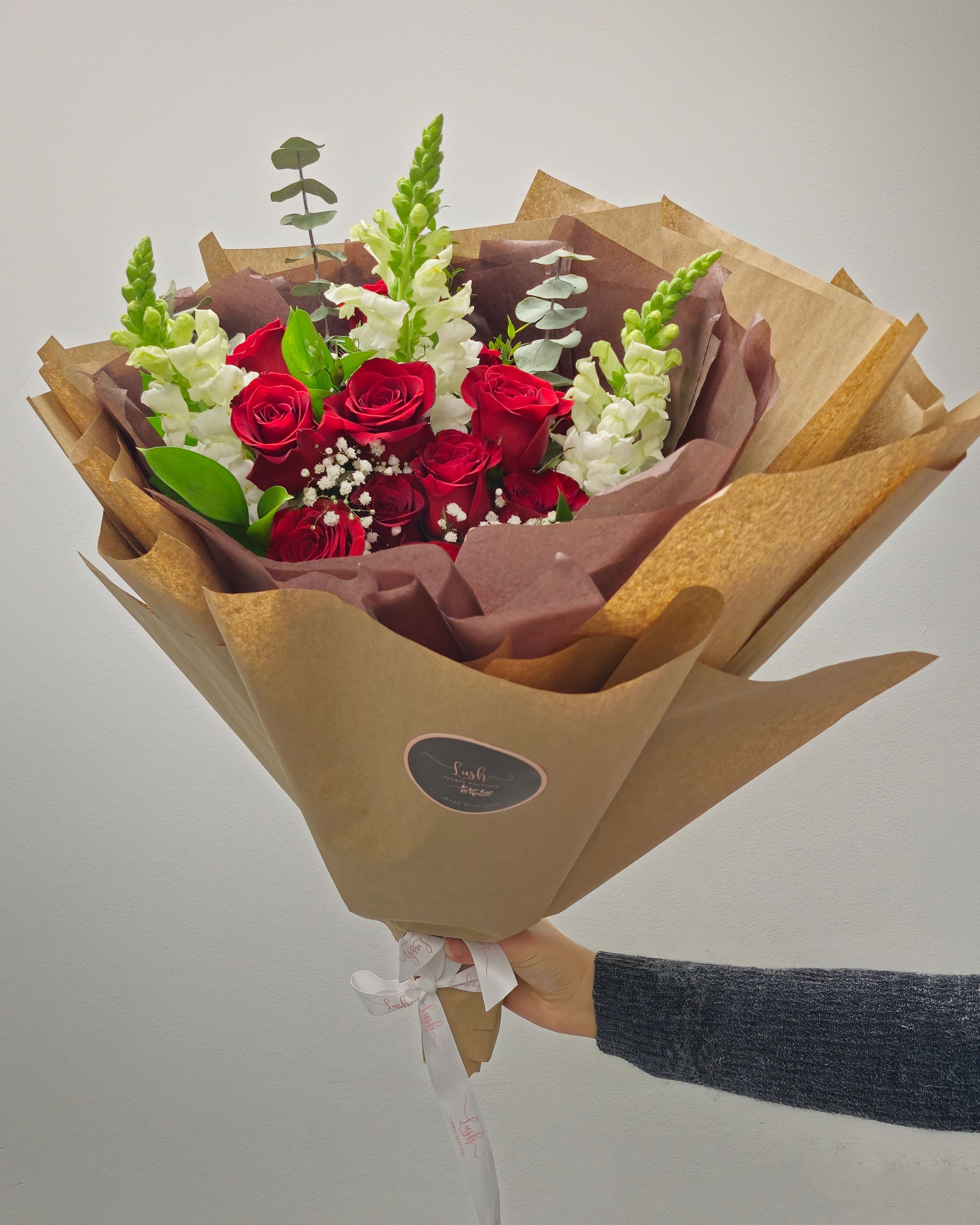 Dozen Amore Bouquet - Make a grand statement this Valentine’s Day with the ultimate bouquet, featuring 12 premium, long-lasting roses arranged to perfection. Encased in our luxurious signature wrap, this breathtaking display of love and devotion is designed to leave an unforgettable impression.