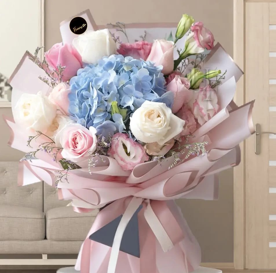 ADMIRATION WRAPPED BOUQUE ADMIRATION WRAPPED BOUQUE - Elevate any occasion with this stunning bouquet featuring blue hydrangea and delicate pink and white roses. Wrapped in elegant pastel paper and tied with a soft ribbon, this arrangement exudes grace, charm, and sophistication, making it the perfect gift for expressing admiration and love.