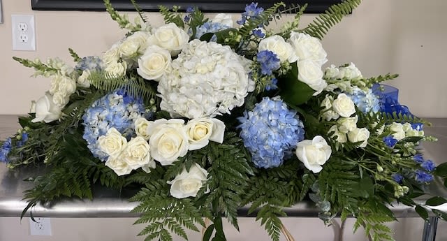 Forever By The SEA Forever By The SEA - Full Casket Cover with blue and white hydrangeas, white roses, white spray roses, blue delphiums, white stock and mixed greens