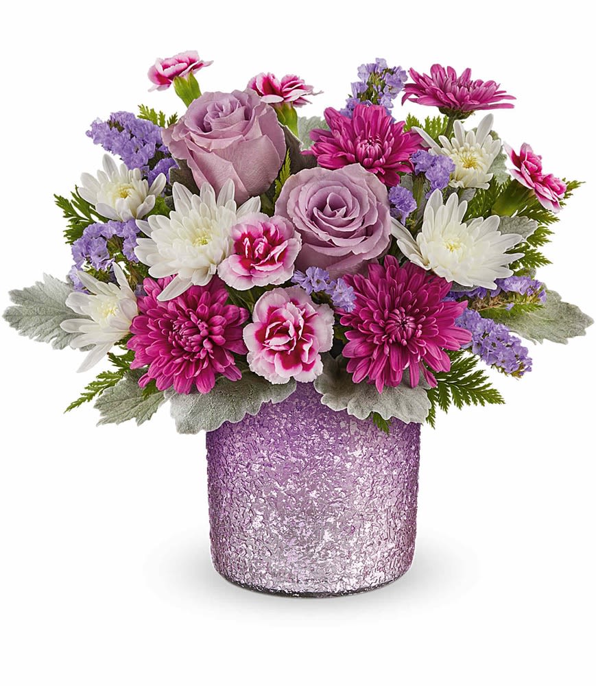 Teleflora's Radiant Reverie Bouquet - Delight Mom with the Sparkling Joy Bouquet, delivered in a pink glass carafe with elegant beaded details. Paired with hot pink roses, pink spray roses, light pink alstroemeria, and other pretty blooms, this keepsake meets FDA tableware standards to safely serve and store drinks, adding beauty to any table year-round.  Surprise her with the Sparkling Joy Bouquet-hot pink roses, pink spray roses, light pink alstroemeria, green carnations, pink miniature carnations, bupleurum, leatherleaf fern, and parvifolia eucalyptus-artfully arranged in the food-safe pink glass carafe with elegant beaded details, a cherished gift for Mom.