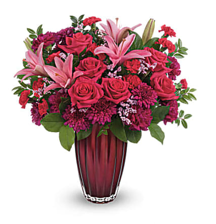 Teleflora's Modern Devotion Bouquet - Mondern arrangement with Pink Asiatic Lilies, Red Roses, Purple Waxflower and Asters with assorted greens in a Red Teleflora Vase.