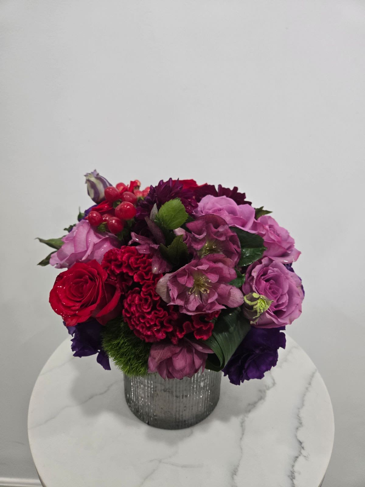 Twilight - Bold and vibrant, this arrangement features deep red roses, rich purple blooms, and lush greenery in a sleek, textured vase—perfect for a modern, elegant touch.
