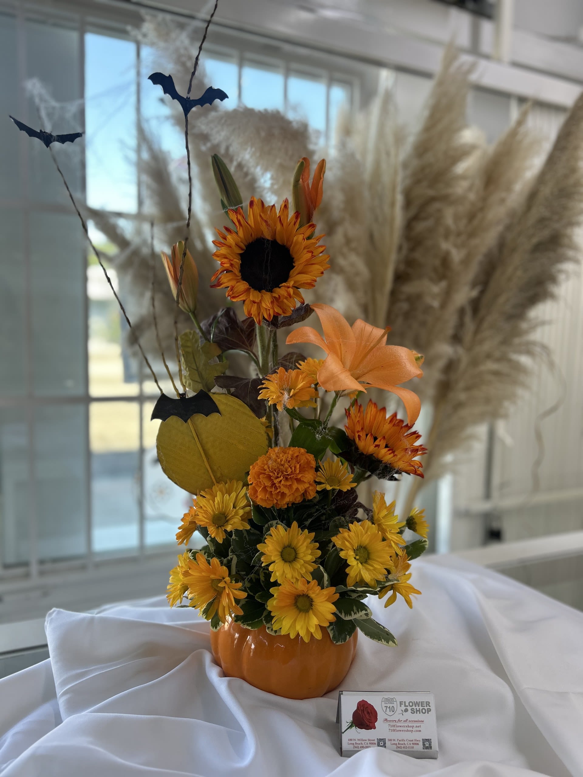 Harvest Enchantment - Harvest enchantment is a festival fall arrangement featuring sunflowers, daisies, and playful bats and a pumpkin vase! Substitutions: If some flowers and/or the vase are not available there will be minor substitutions.  