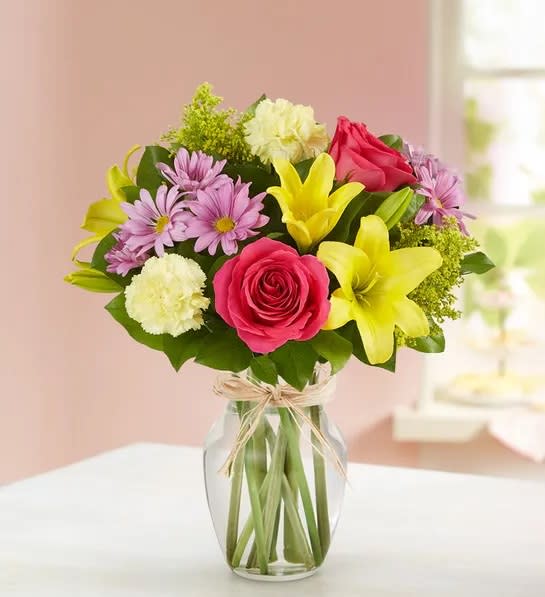 Fields Of Europe® For Spring - Our best-selling spring bouquet is inspired by the traditional, hand-tied arrangements found in flower markets throughout Europe. Gathered with a mix of vibrant blooms inside a classic glass vase, it brings a cheerful taste of old-world charm to the people you care about.  All-around arrangement with hot pink roses, yellow Asiatic lilies and carnations, lavender daisy poms; accented with assorted greenery