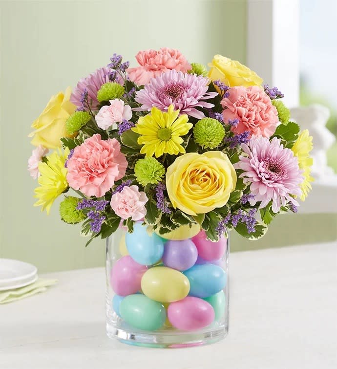 Easter Egg Stravaganza - Our pastel bouquet brings fresh-picked spring beauty—and plenty of fun—into every home at Easter. Softly-colored blooms are gathered in a clear glass cylinder vase filled with colorful eggs for a uniquely playful touch. Surprising family &amp; friends or decorating your own table, this gift’s sure to make the holiday celebration even more special.