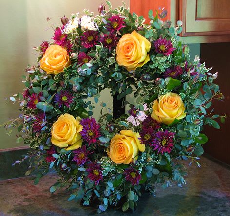One Last Hug - A wreath of seasonal flowers, roses, and greenery is a beautiful way to remember a loved one. Appropriate for memorial and funeral services.