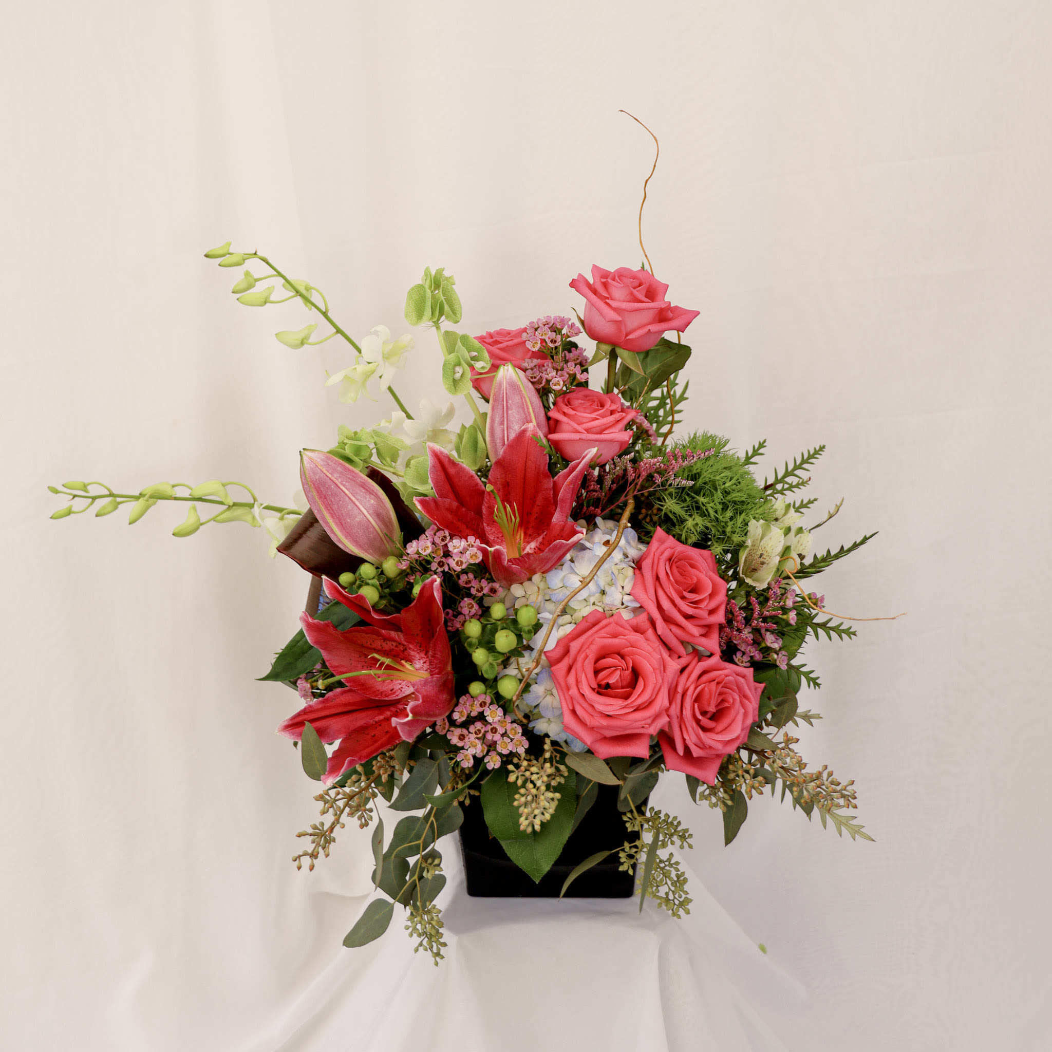 The Earth Sings in Flowers The Earth Sings in Flowers - This arrangmnet is composed of pink roses, lilies, and orchids and features a variety of high class greenery. It is a gorgeous arrangement to give to a significant other or to show appreciation for someone this season.