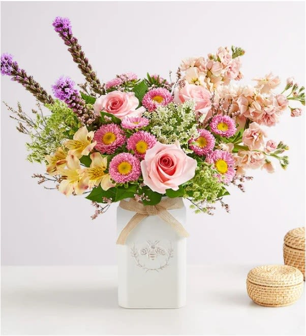 Honey Bee Buzz for Spring Honey Bee Buzz for Spring - Get them buzzing for spring! Featuring a glorious mix of blooms in shades of pink, purple, and peach, our eye-catching bouquet dazzles with color and texture. Designed in our Sweet As Can Bee artisanal vase, featuring an adorable honey bee and raffia bow, it’s a gift that adds charm and beauty to any decor.