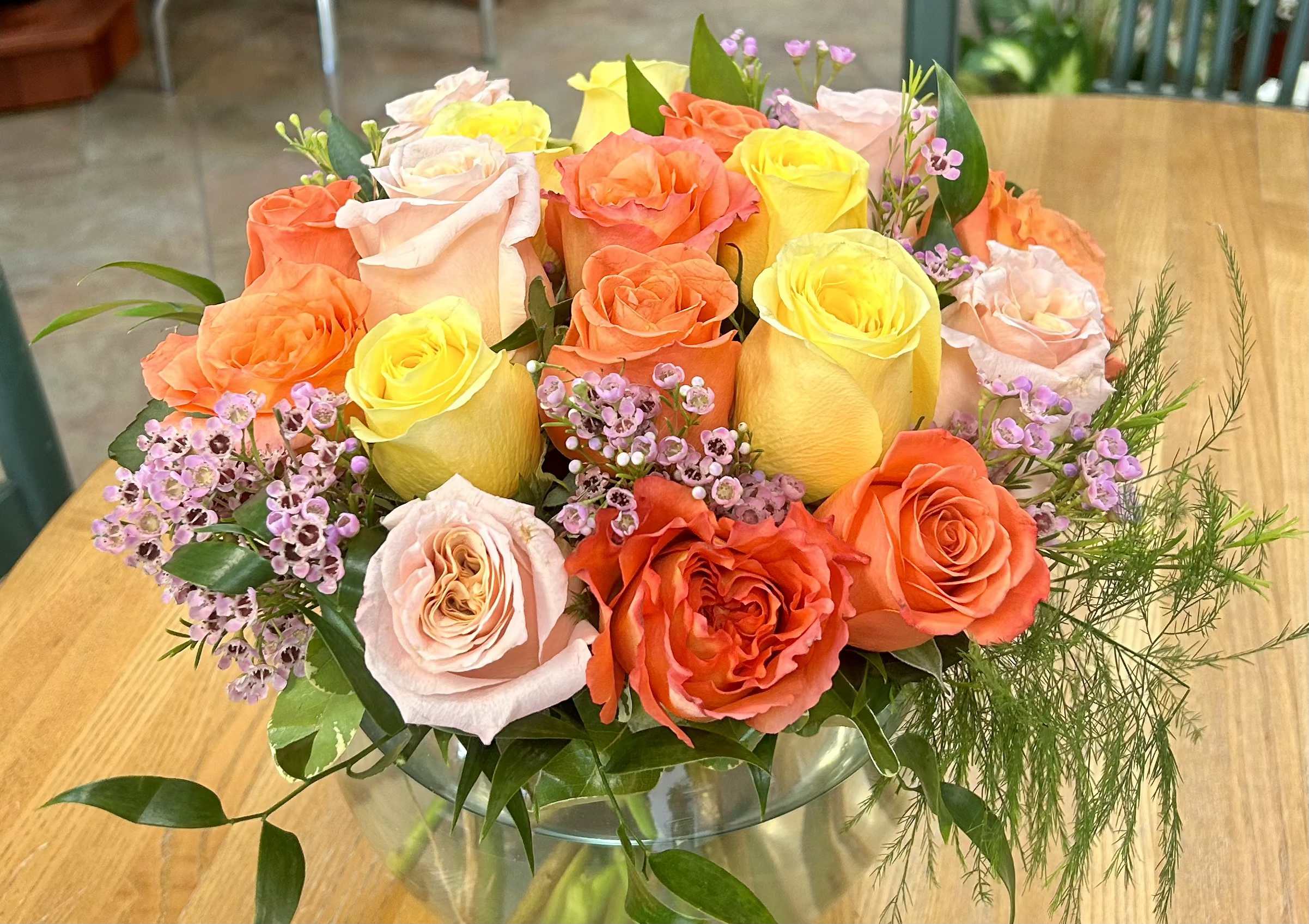 CFM123 - A low compact arrangement of assorted colored roses arranged with mixed greenery and filler to accent.