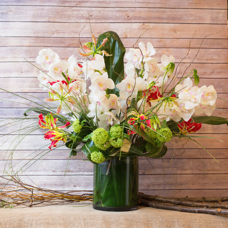 JAPANESE ARRANGEMENT JAPANESE ARRANGEMENT - CYLINDRICAL VASE WITH JAPANESE GLORIOSA, WHITE CYMBIDIUM ORCHIDS, VIBURNUM, THAI LEAF, AND BEAR GRASS.