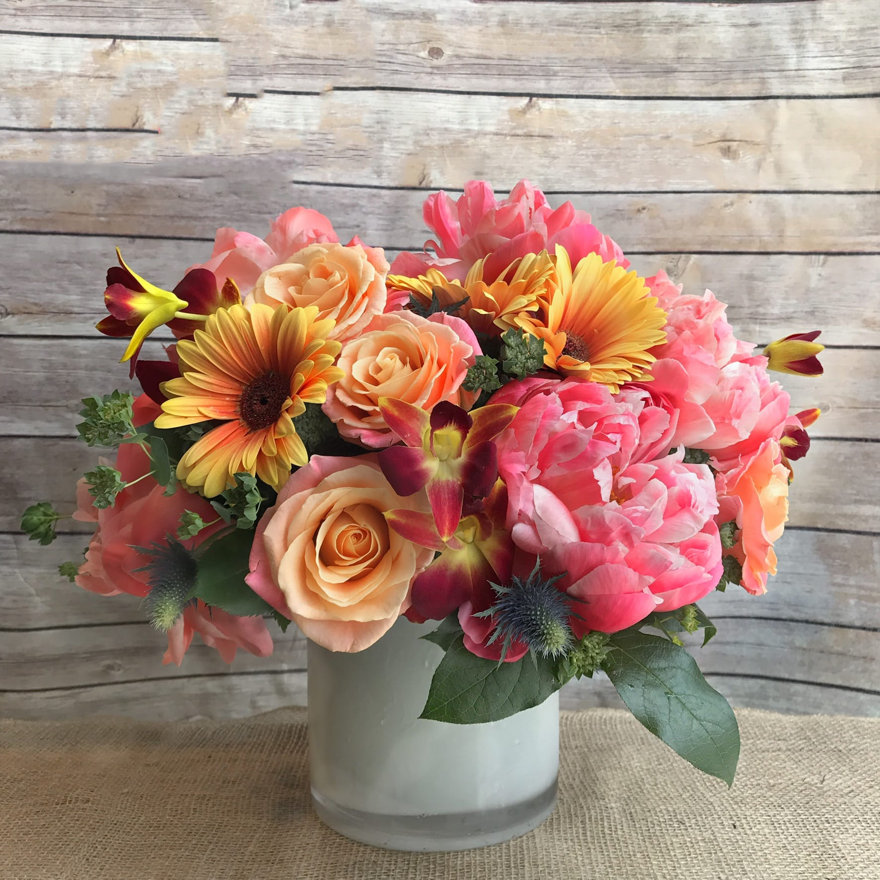 VAVA VOOM VAVA VOOM - INFUSION OF MODERN AND GARDEN ARRANGEMENT IN WHITE GLASS CONTAINER WITH CORAL CHARM PEONIES, DENDROBIUM ORCHIDS, GERBERA DAISIES,AND FREE SPIRIT ROSES.