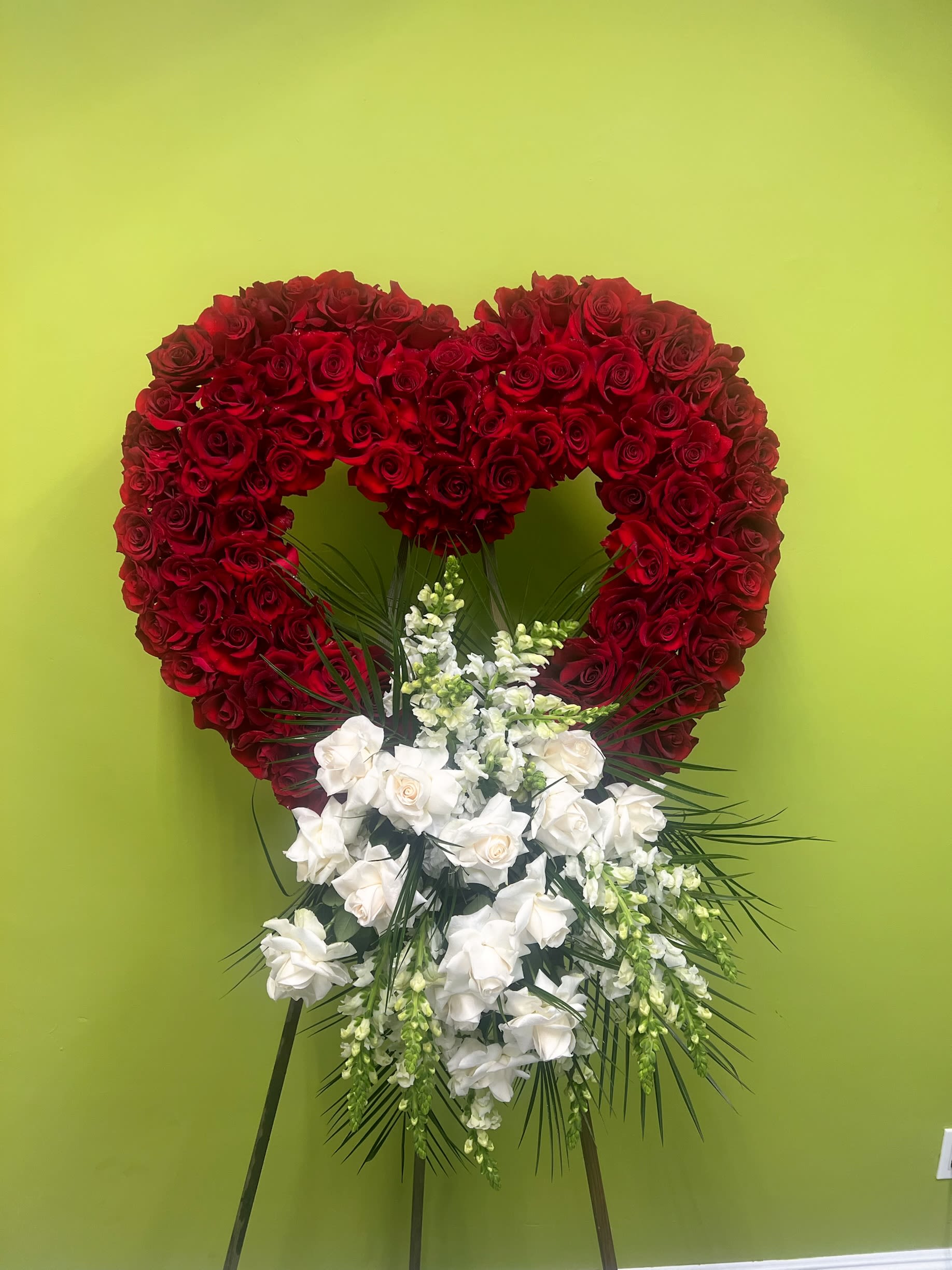Forever in Our Hearts Wreath Forever in Our Hearts Wreath - red rose heart with lush white florals and cascading greenery, symbolizing deep love and heartfelt remembrance. This funeral tribute is a beautiful way to express condolences and pay final respects.