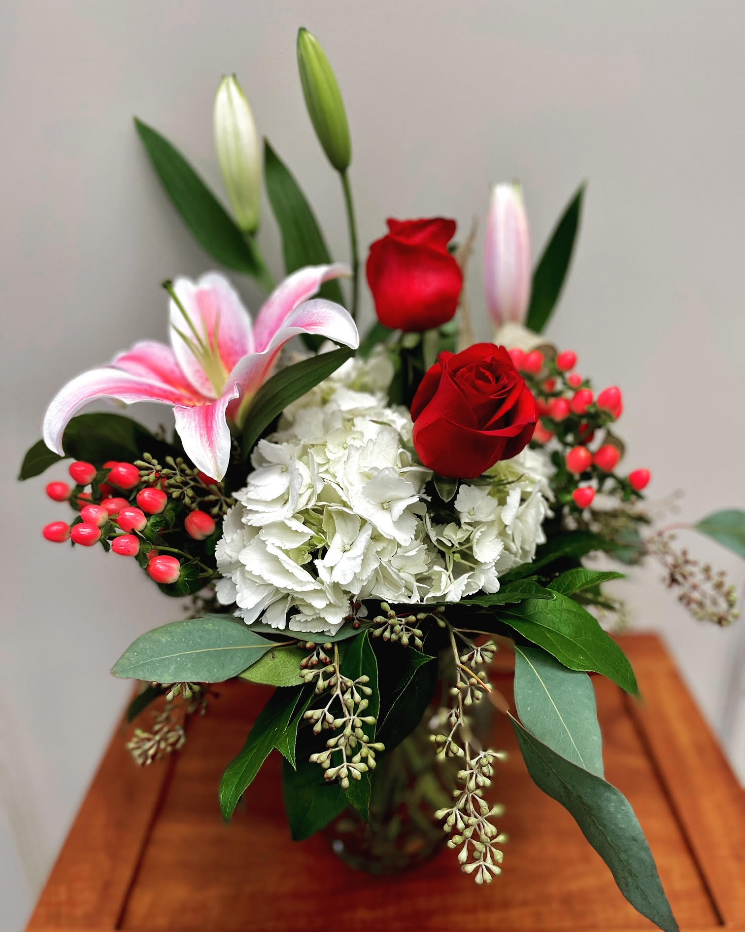 Lovers Cove - Fragrance &amp; beauty fight for attention in this beautiful design perfect for your Valentine or special person in your life. Hydrangea, stargazer lilies, roses and coffee berry are nestled in seasonal greens and topped off with a burlap ribbon. A winner!