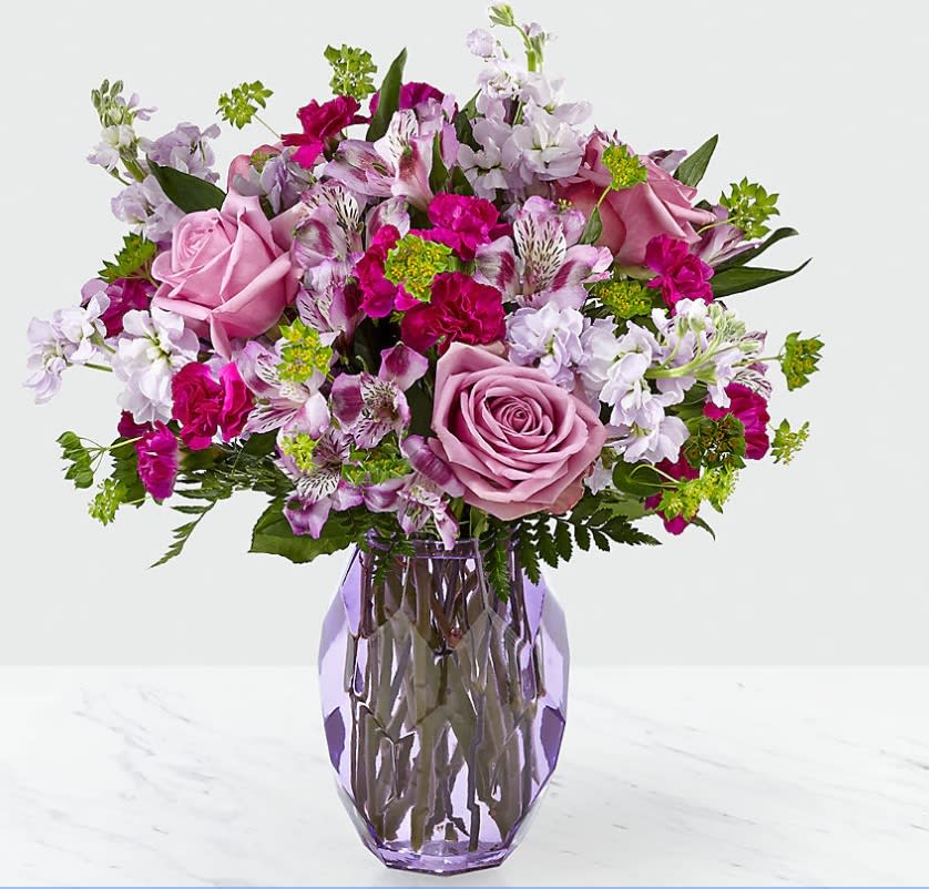 Full of Joy Classic (lavender) - From delighting your loved ones to filling your home with joy, the effect flowers can have on a room is just wonderful. This arrangement features lavender roses, stock and alstroemeria and is complemented by violet mini carnations and bupleurum within a purple glass vase. 