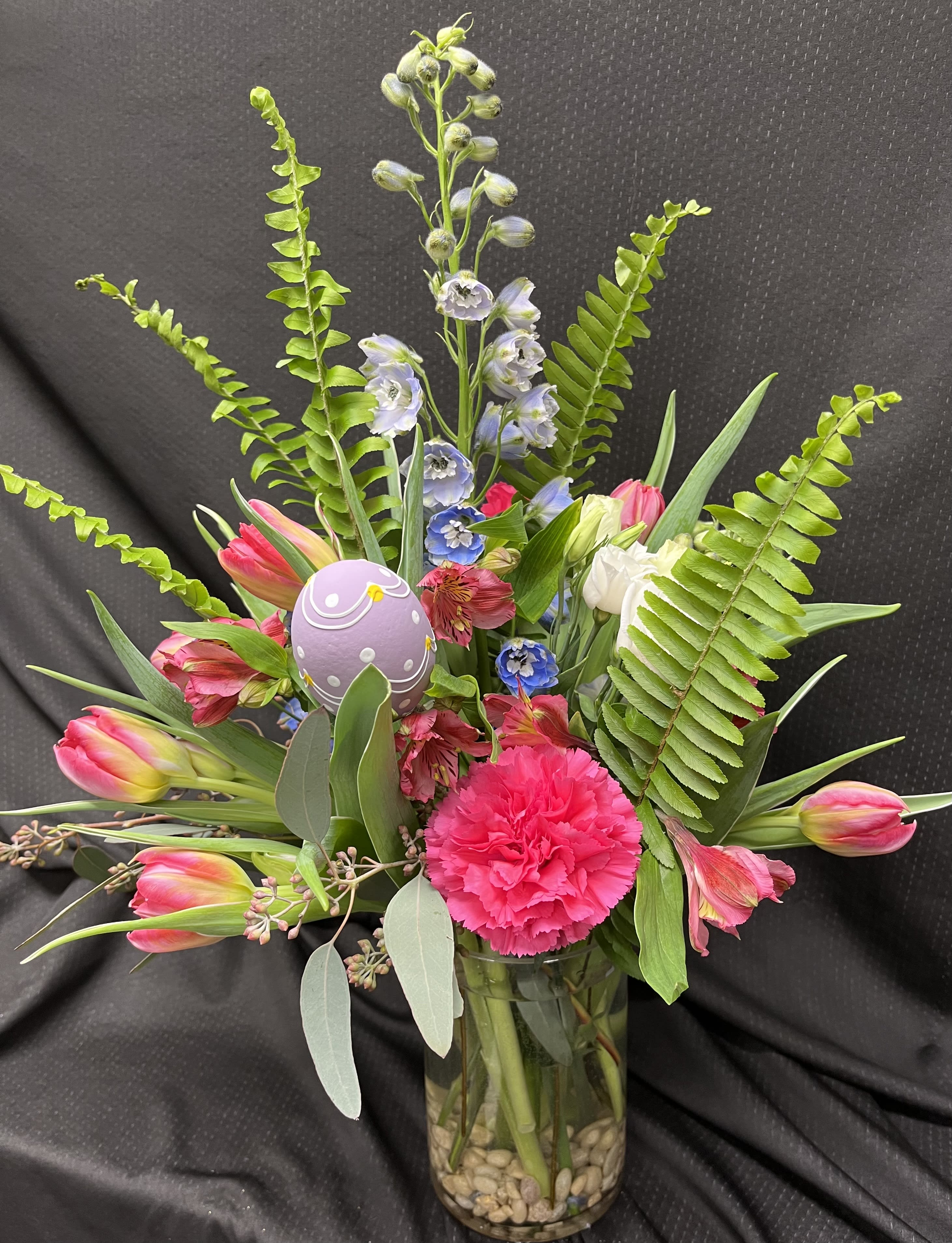 Springtime - This arrangement is made up of tulips, delphinium, alstroemeria, and carnations with a little extra decoration in a clear vase.  
