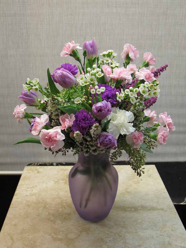 Lavender Pink Mix (SM-13) (will be in clear glass vase) - Tulips, Carnations, Wax flowers and more in a small lavender glass vase. 