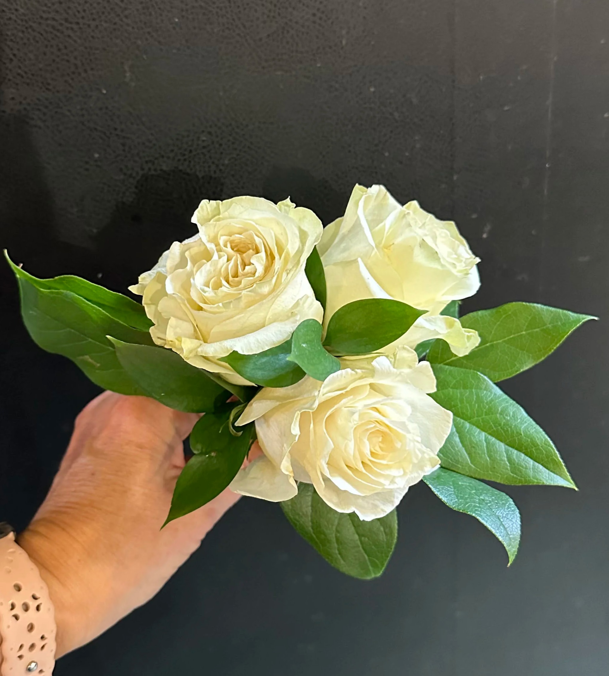 White Rose Posy - Get ready to steal the spotlight at prom with our hand-held mini-bouquets! Our 3-white rose posies are the perfect accessory to enhance your prom look. With its classic and tidy appearance, the posy adds a charming touch to any attire. Each posy comes with stems neatly wrapped in white  satin ribbon.